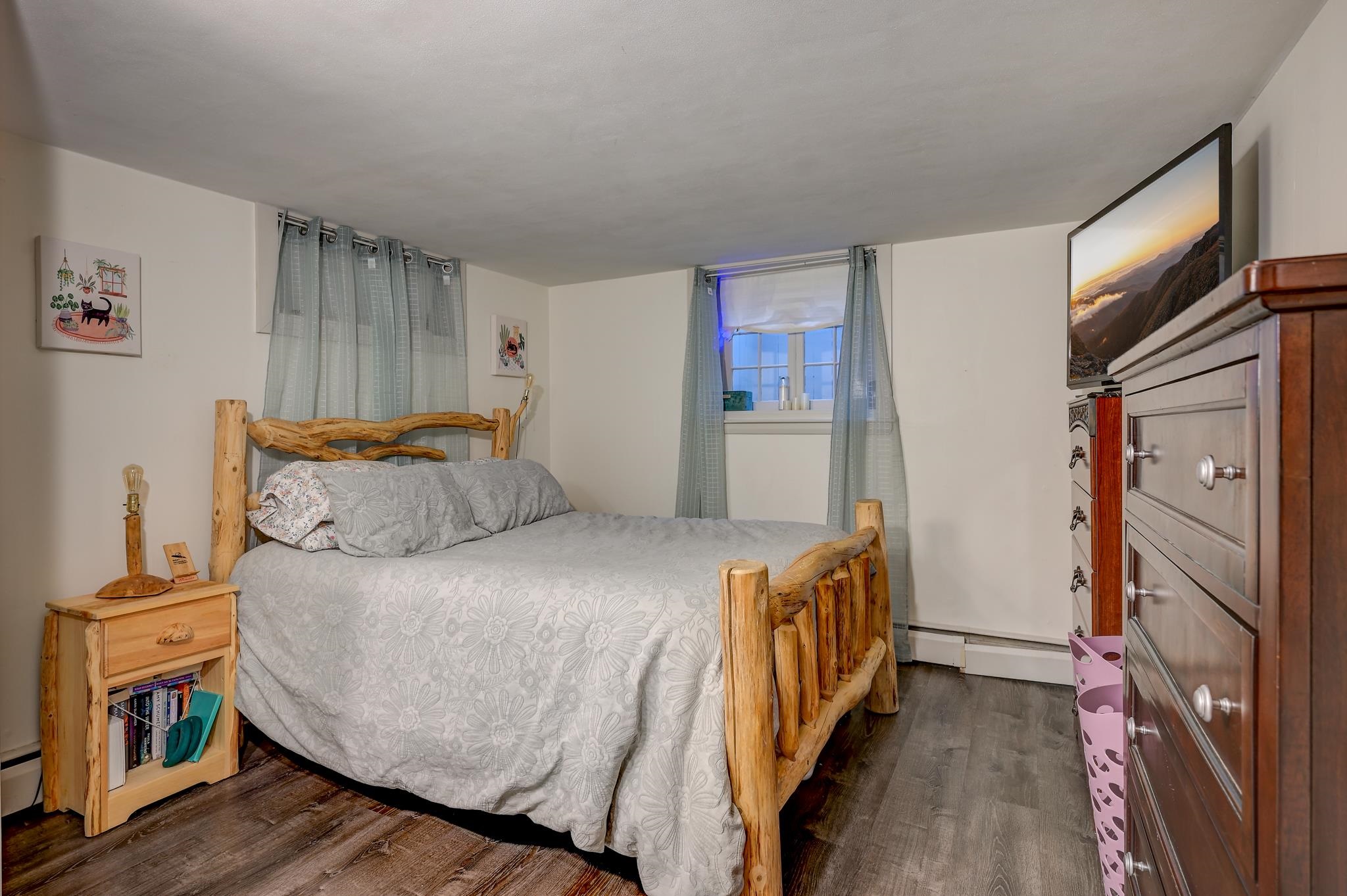 Bedroom with a rustic log bed, gray floral bedding, and pale blue curtains.