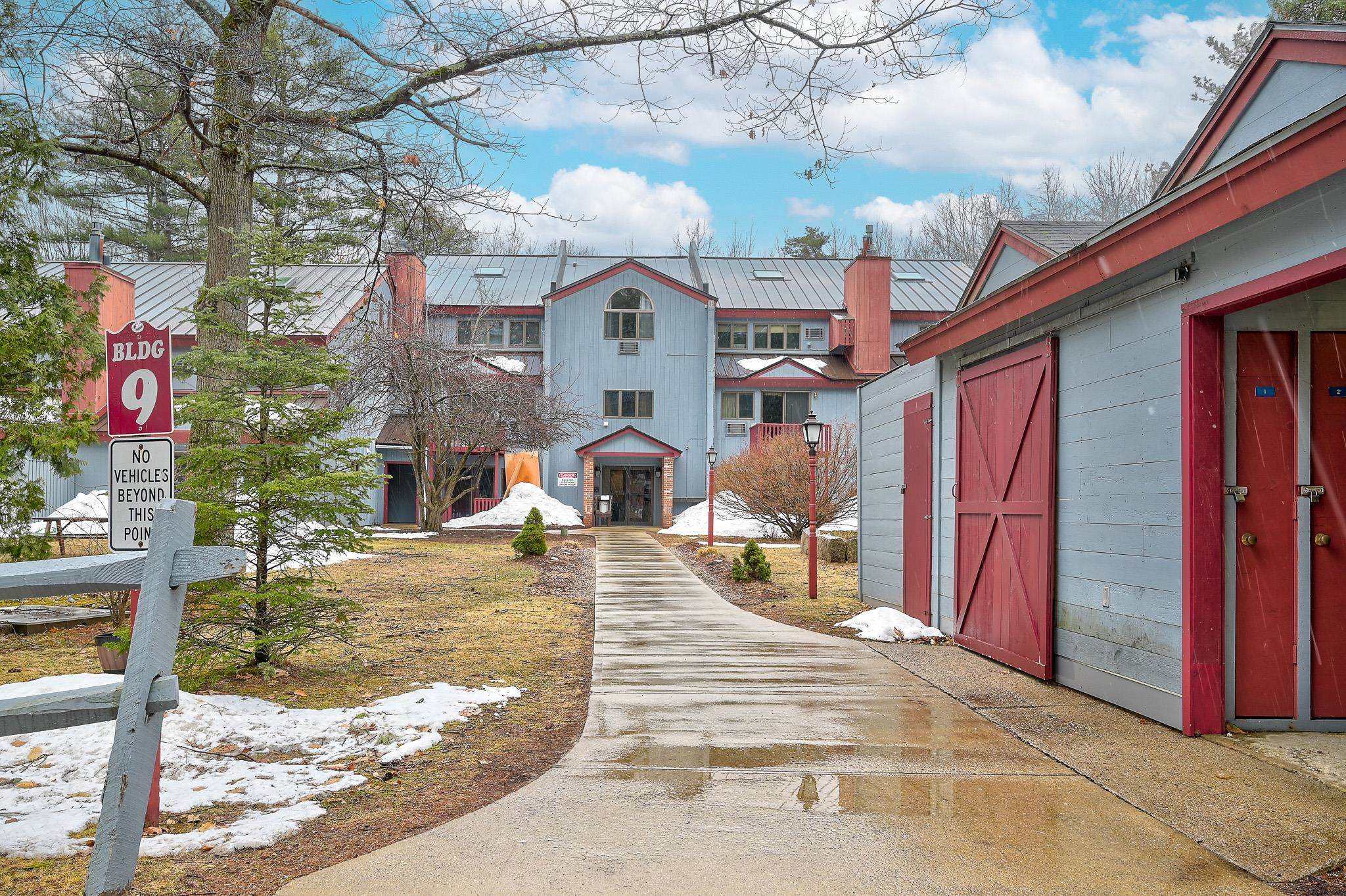 Blue and red multi-unit building with a walkway, snow patches, and a Building 9 sign.