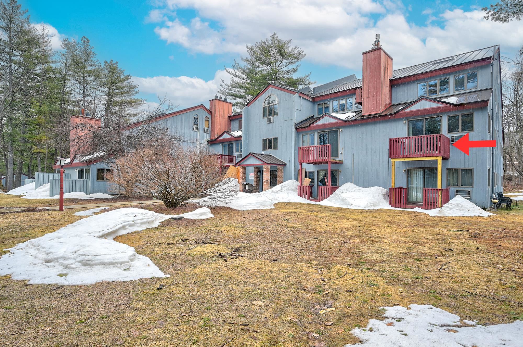 Condominium exterior with a red arrow pointing to an upper-floor balcony on the right.