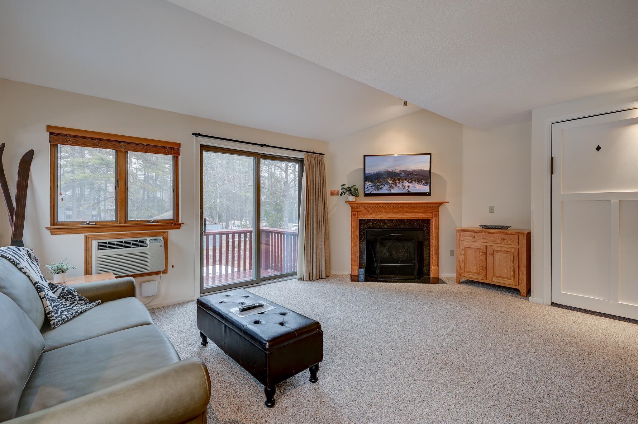 Living room with a wood-trimmed fireplace and sliding doors overlooking a snow-dusted deck.
