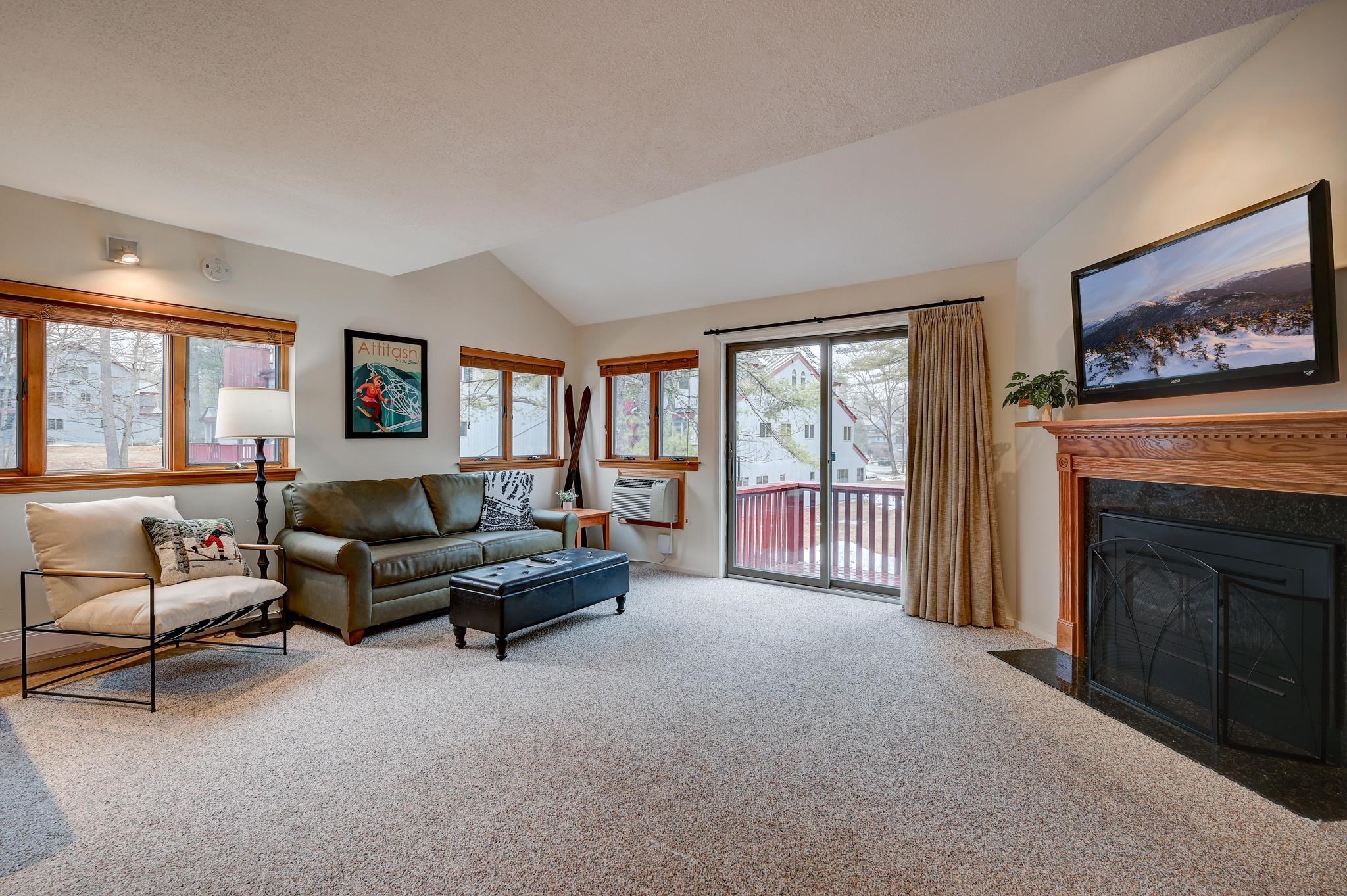 Furnished living room with a wood-trimmed fireplace and sliding glass doors to a balcony.