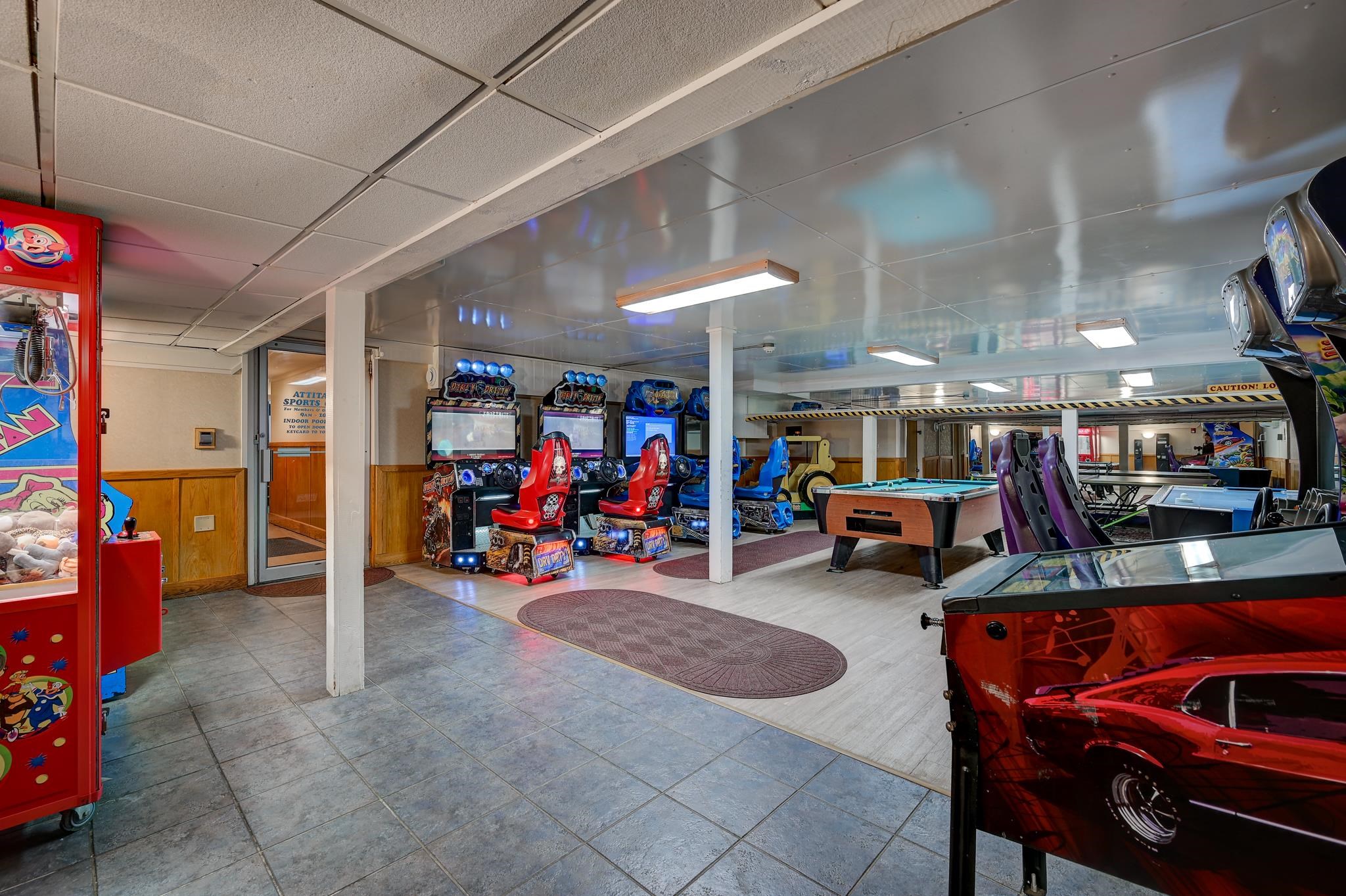 Game room with arcade machines, pool tables, and air hockey tables.