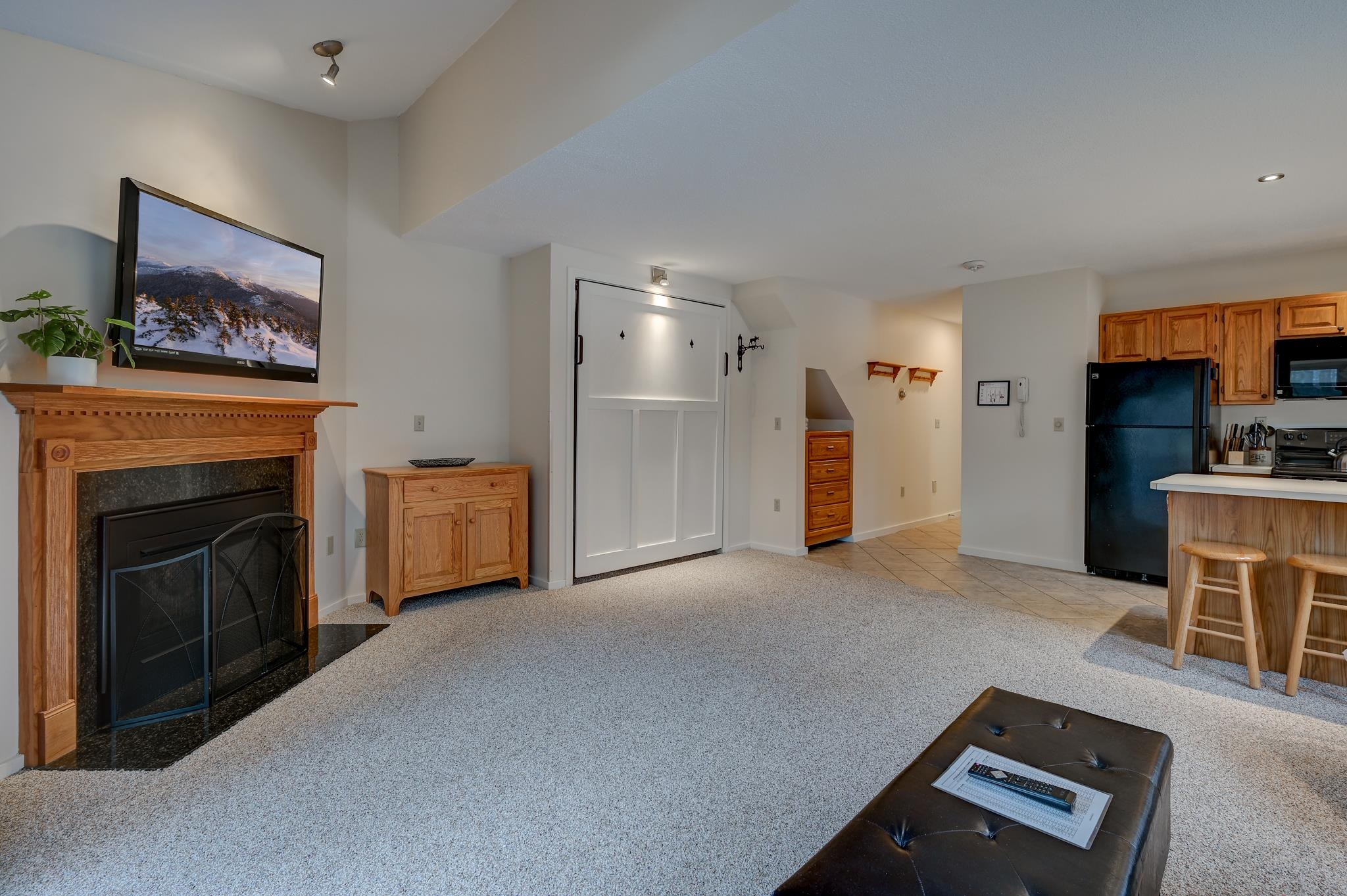Living room with a wood-trimmed fireplace and an open kitchen with breakfast bar.