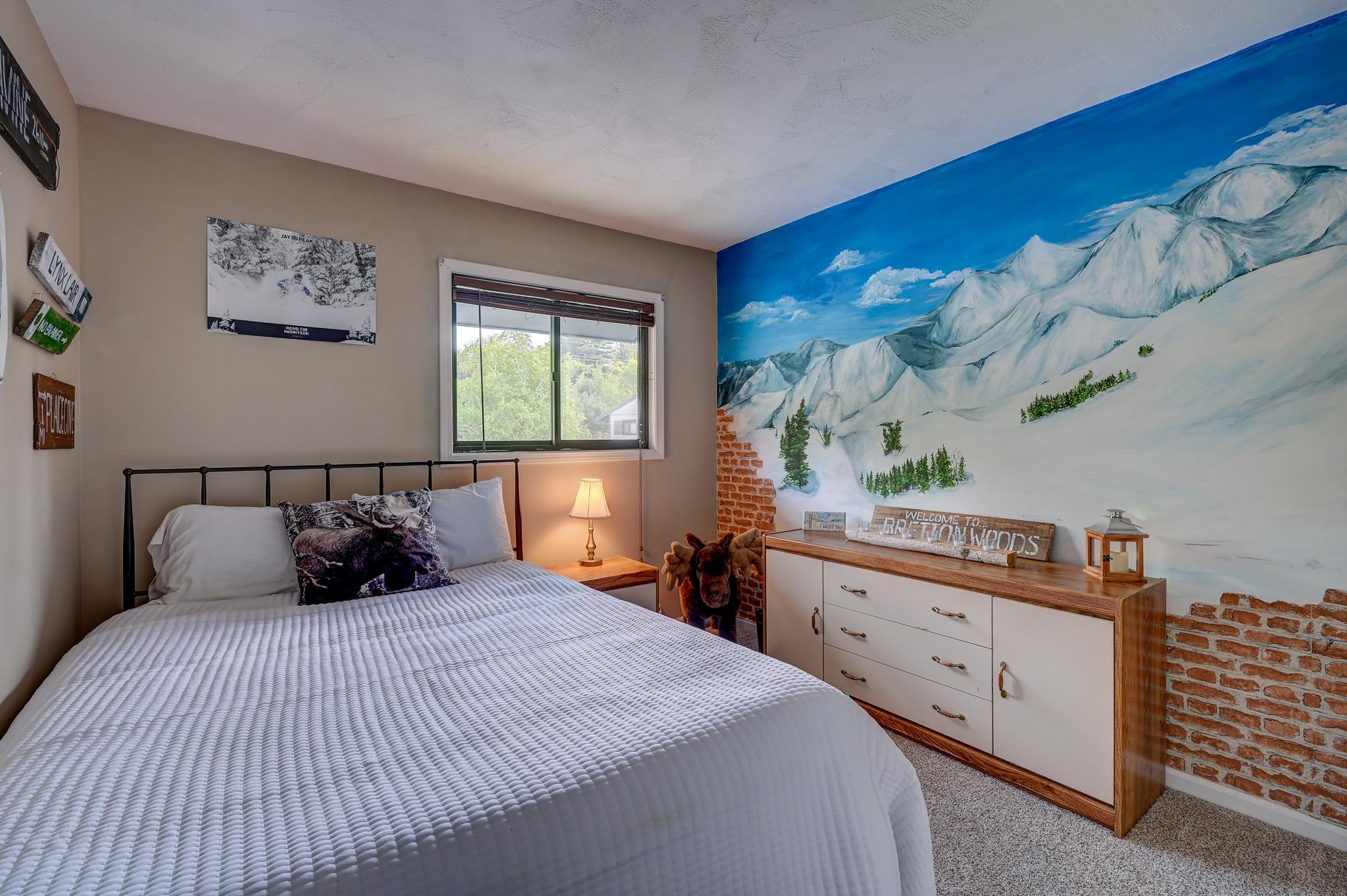 Bedroom with a white quilted bed and a large snowy mountain mural.