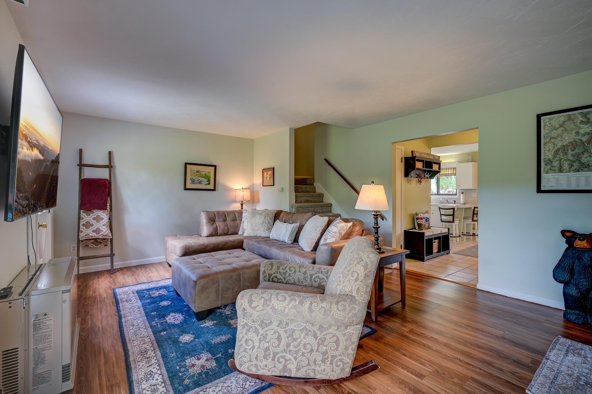 Living room with a sectional sofa and patterned armchair, opening to the kitchen and dining area.