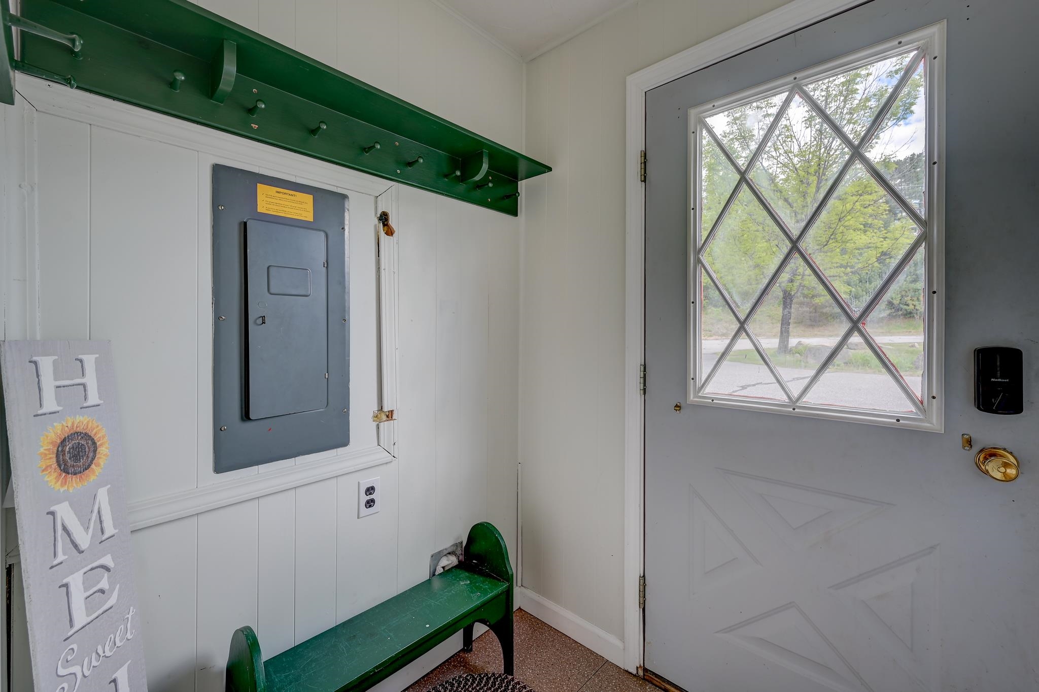 Entryway with a green bench and coat rack beside a diamond-pane front door.