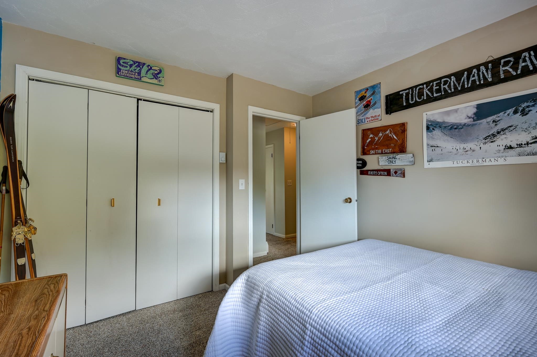 Bedroom with a white-covered bed, large sliding-door closet, and ski-themed wall decorations.