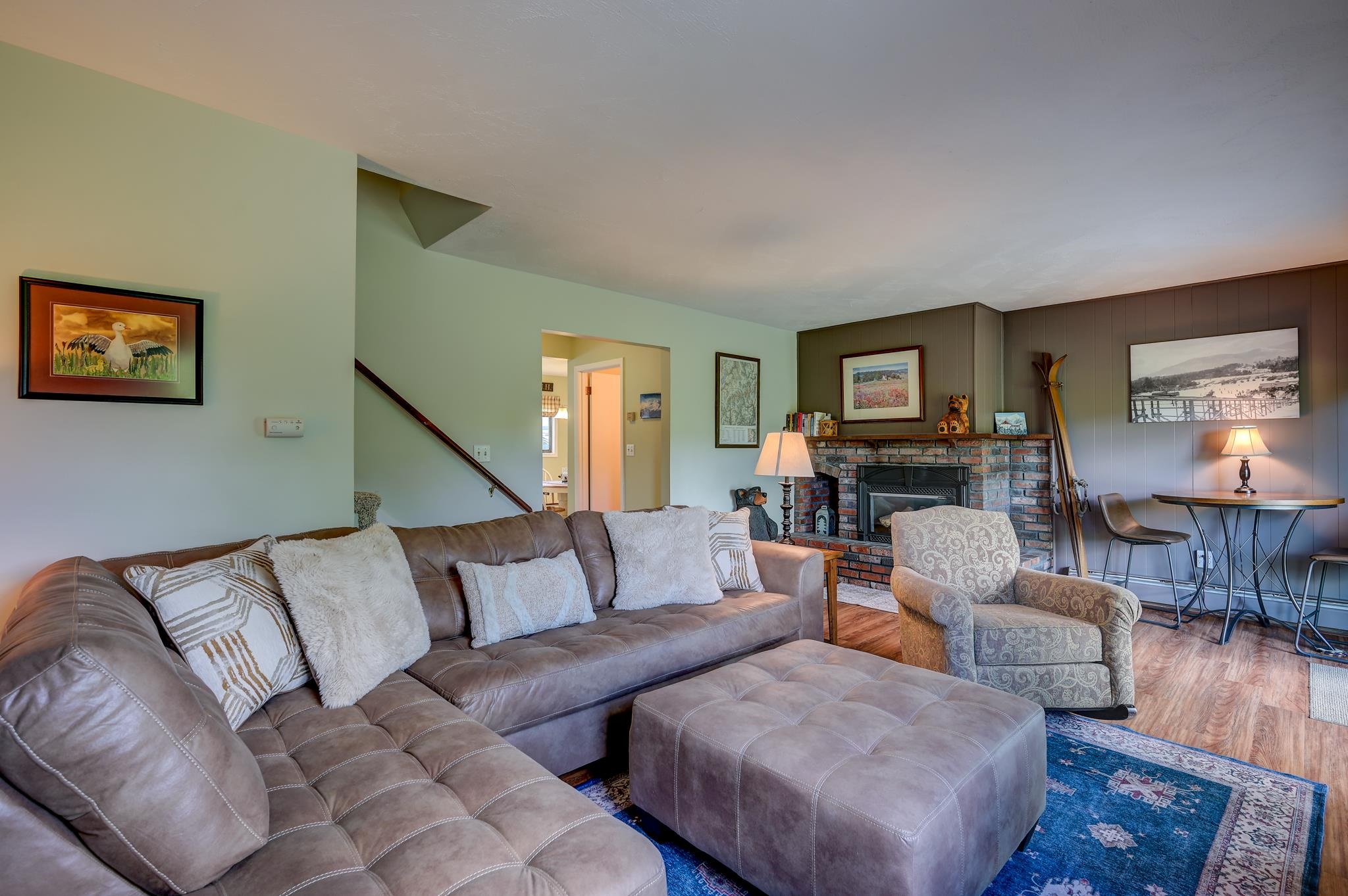 Living room with a large sectional sofa, blue patterned rug, and brick fireplace.