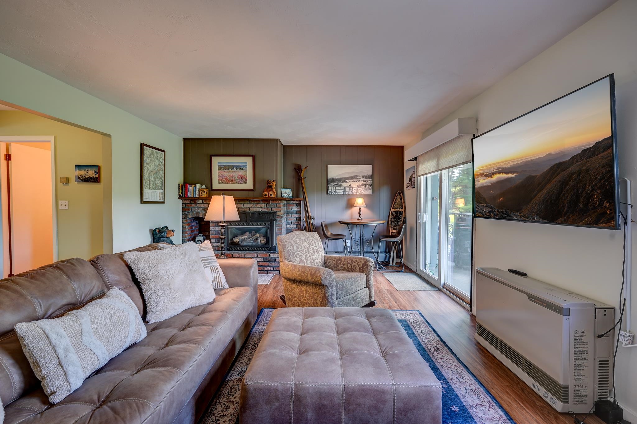Living room with a brick fireplace, leather sofa, and sliding glass doors.