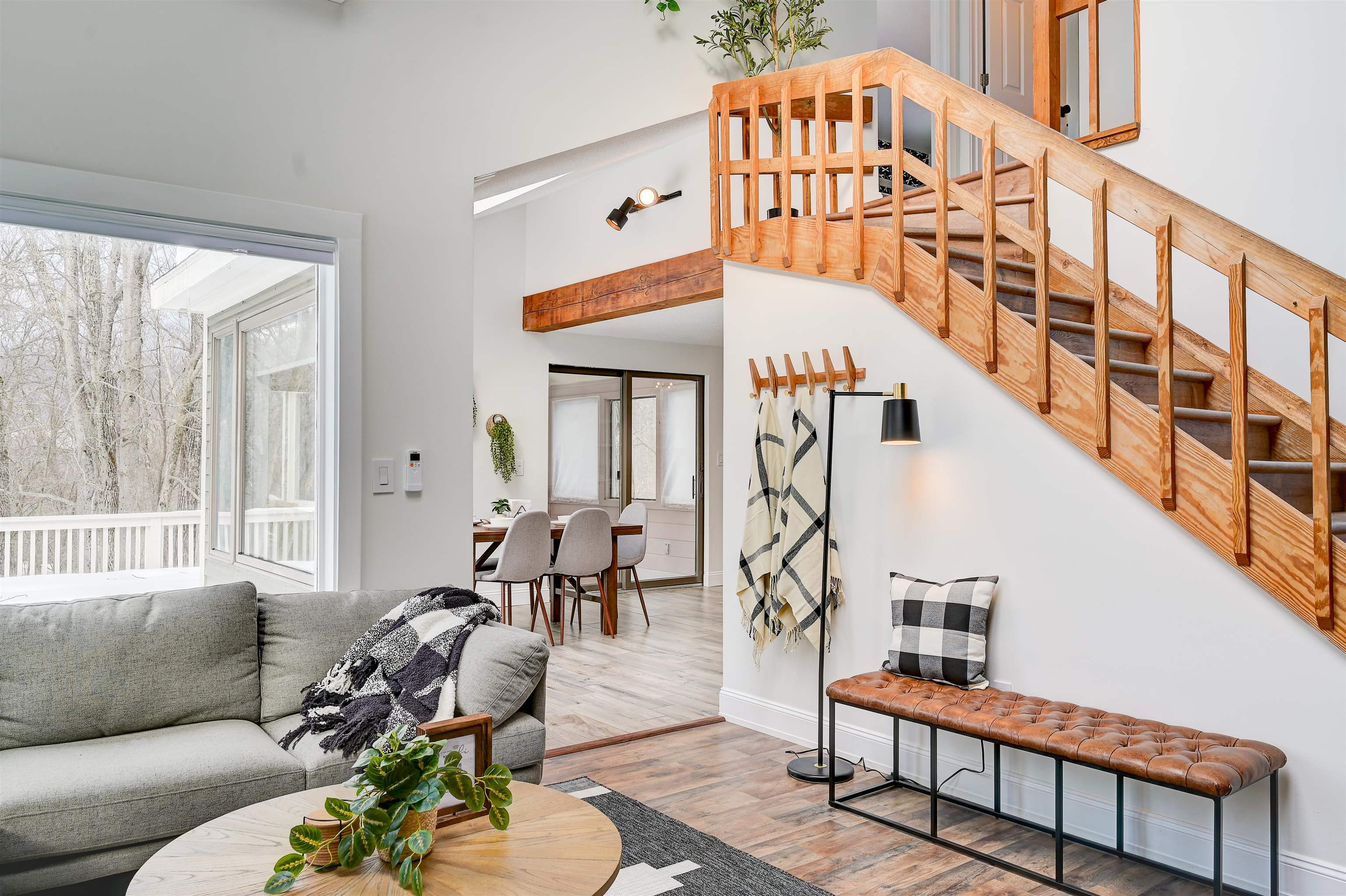 Open living room with a natural-wood staircase, gray sectional, and sliding doors overlooking a snowy deck.