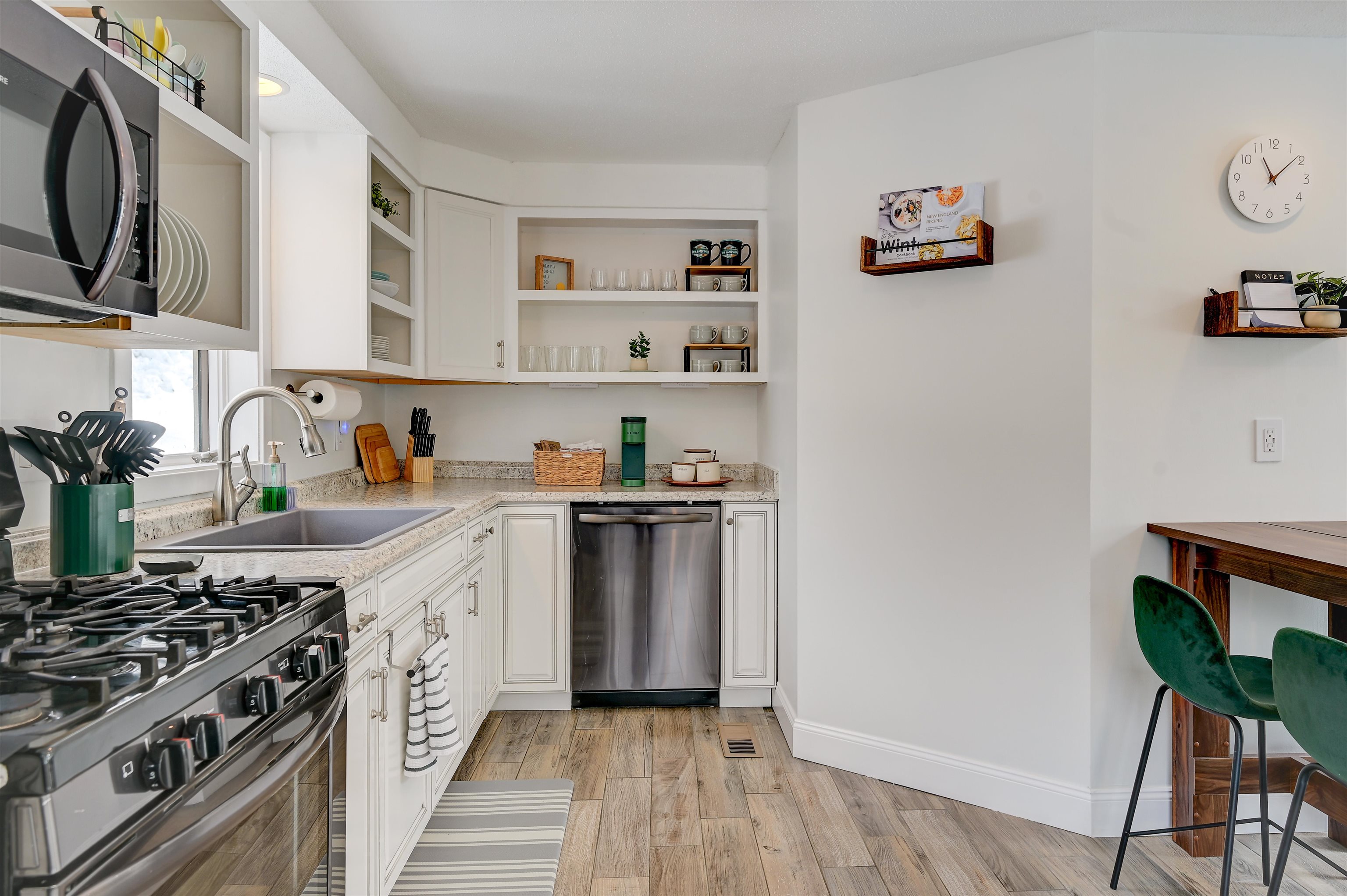 Kitchen with white cabinets, granite counters, stainless steel appliances, and a small dining area.