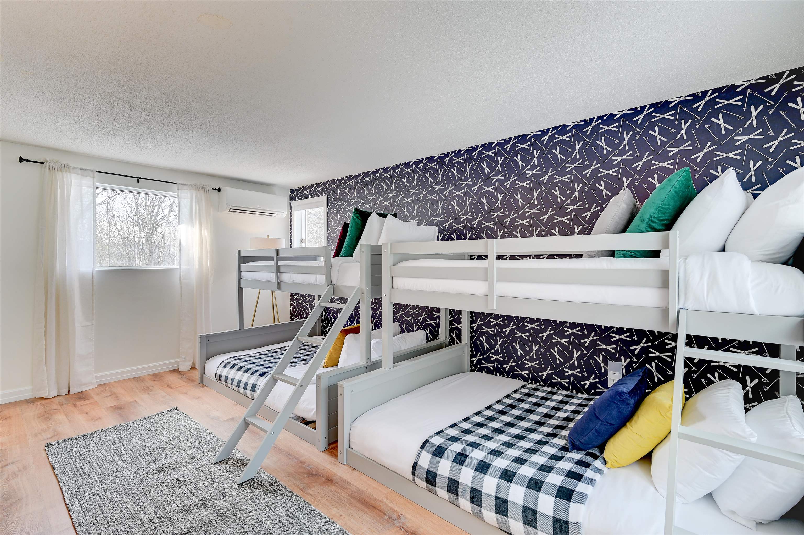Bunk bedroom with checkered bedding, colorful pillows, and a navy patterned accent wall.
