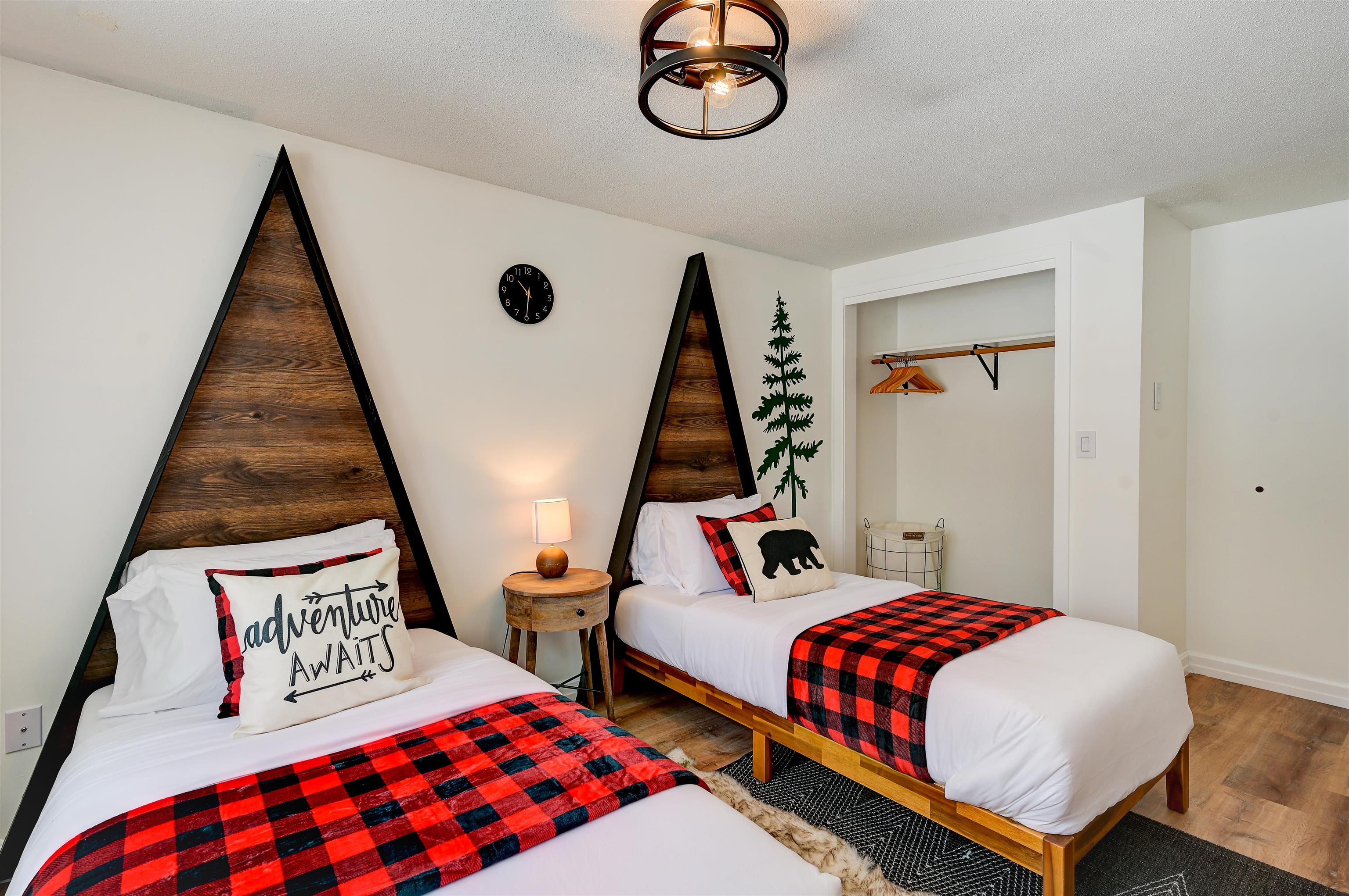 Bedroom with twin beds, triangular wood headboards, and red-and-black plaid throws.