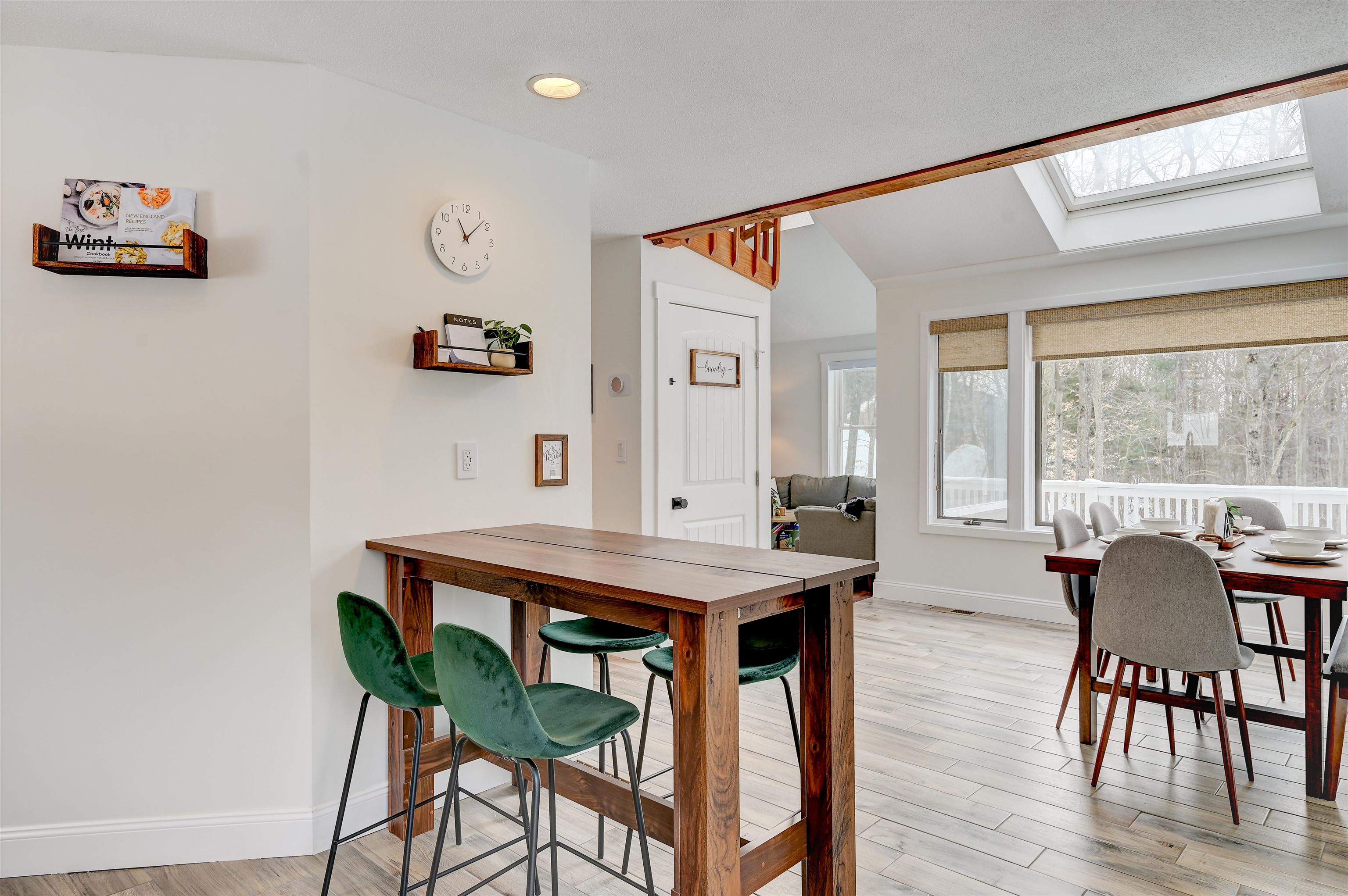 Dining area with rustic wood tables, green chairs, and a skylight overlooking a snowy wooded setting.