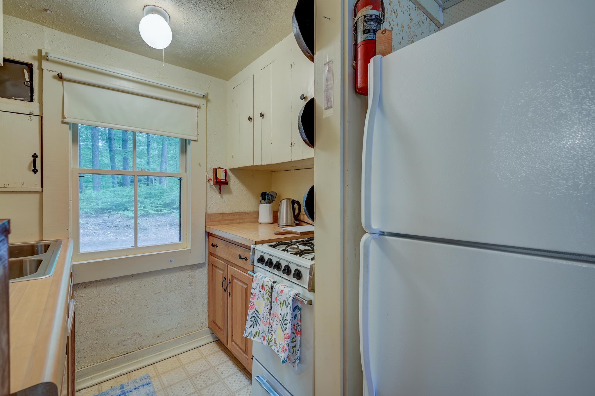 Kitchen with wood cabinets, a gas range, and a window overlooking trees.