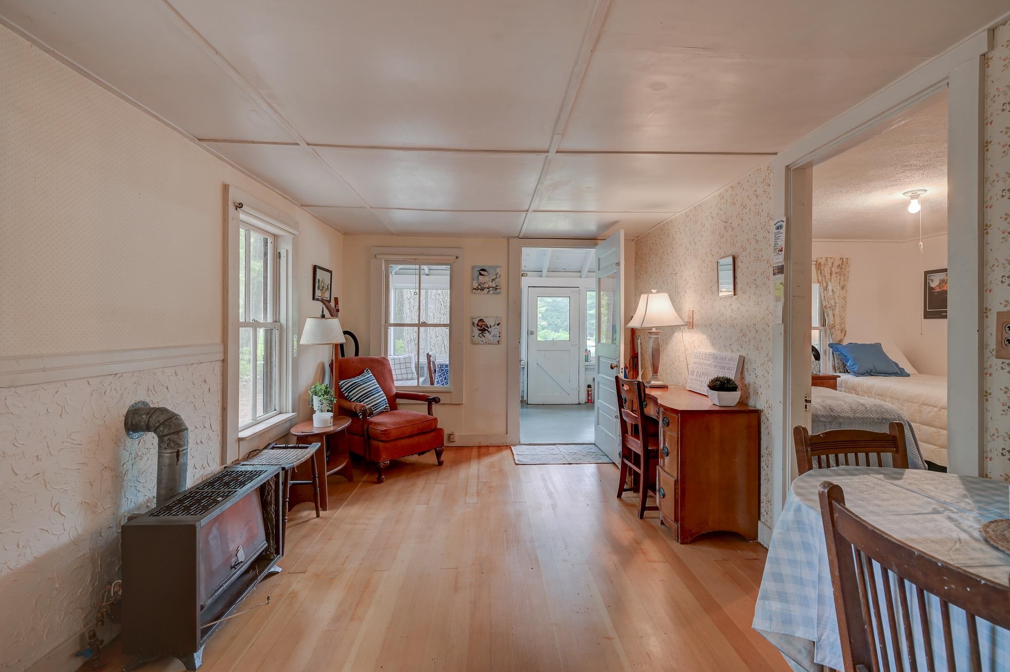 Living and dining area with light wood floors, a freestanding stove, and a red armchair.