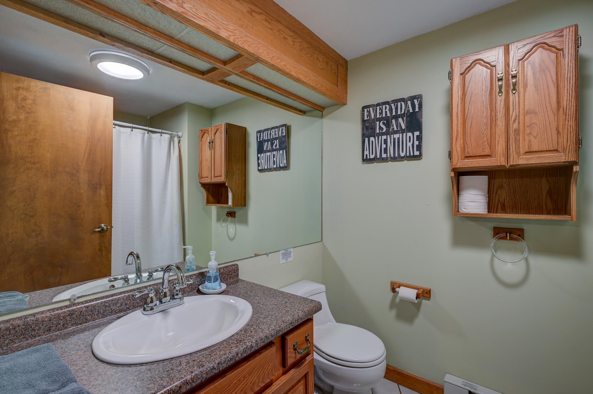 Bathroom with a granite vanity, wood cabinets, and an “Everyday Is an Adventure” wall sign.