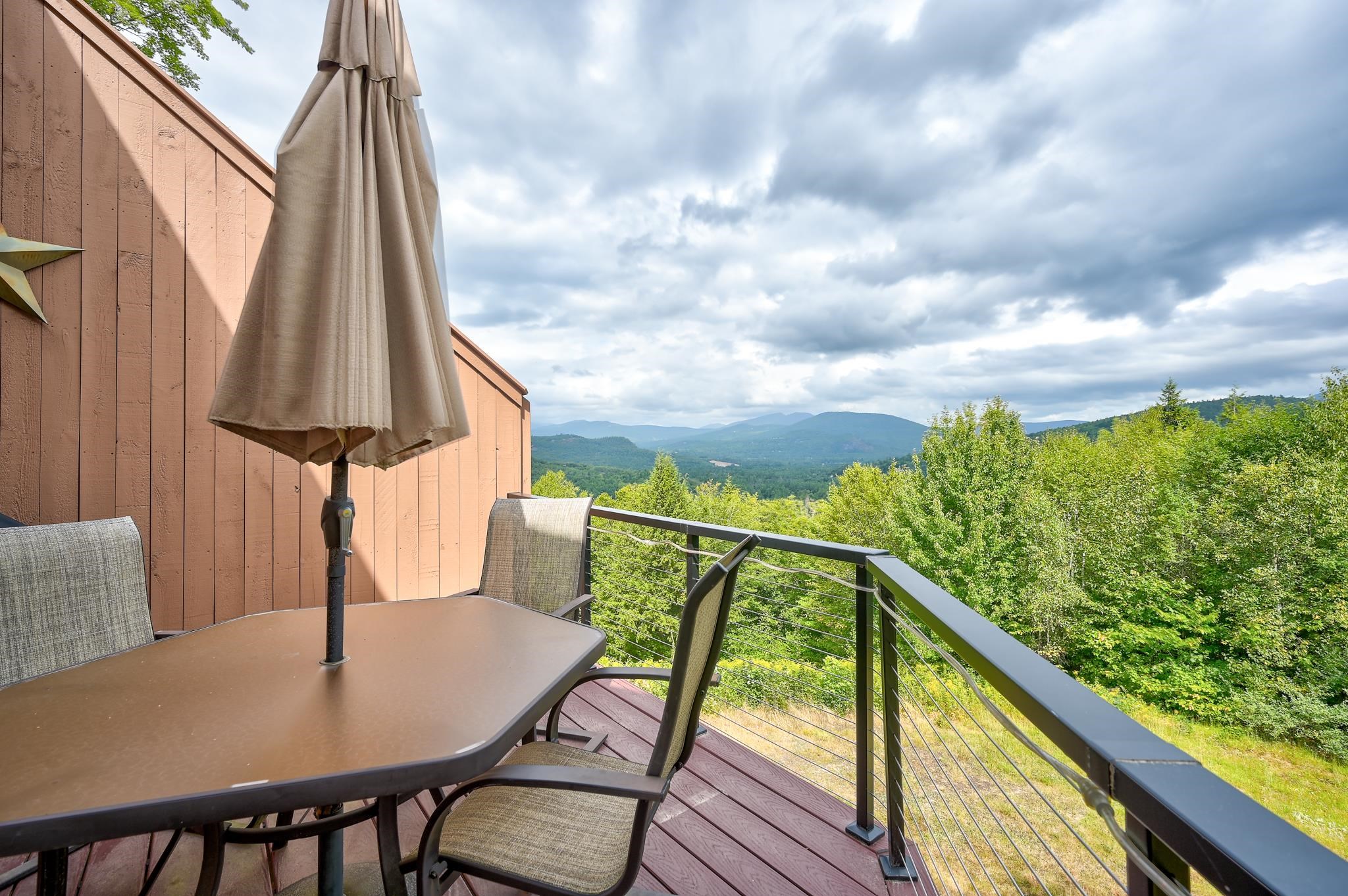 Furnished deck overlooking forested hills and distant mountains.