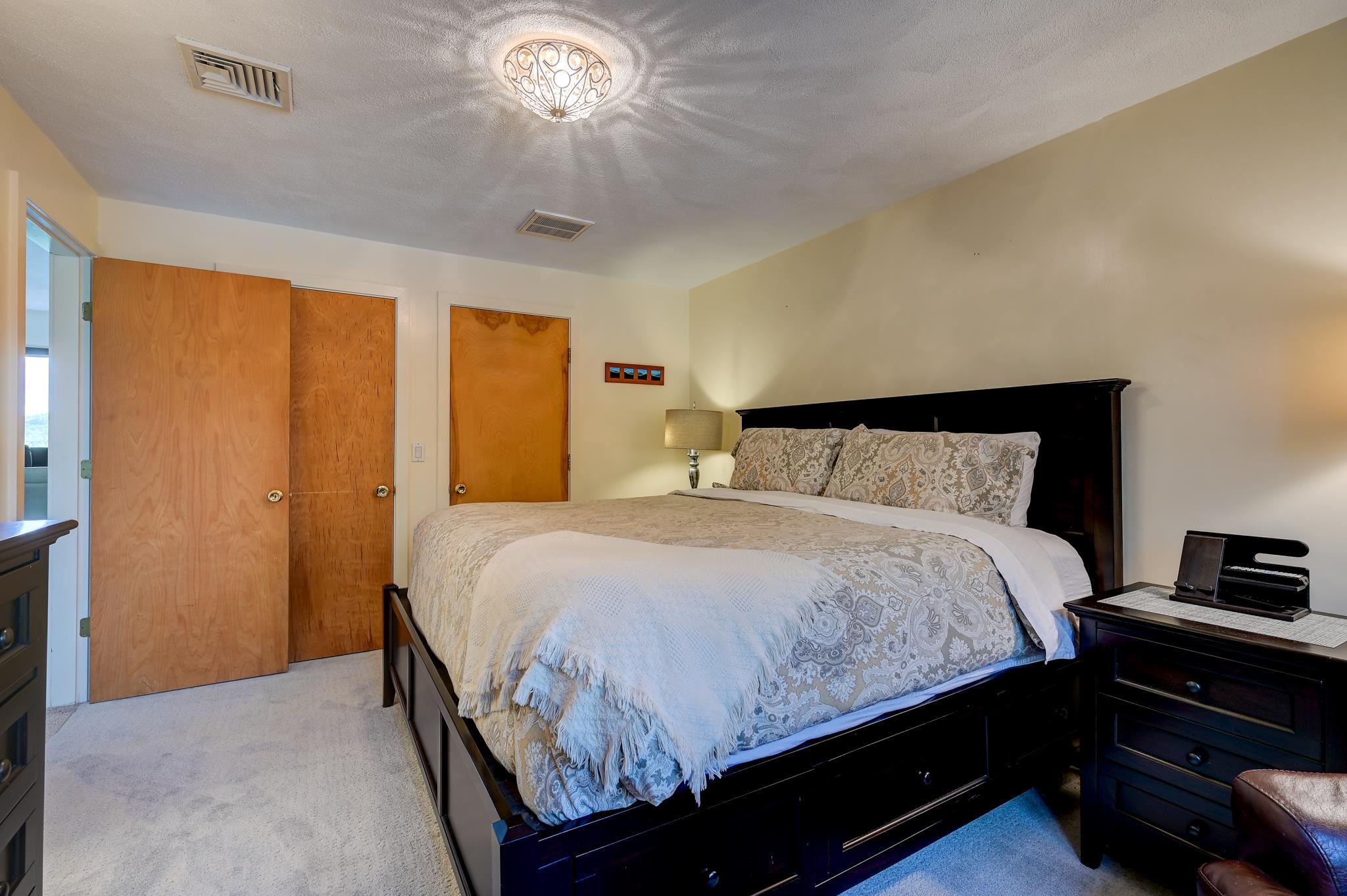 Furnished bedroom with a large dark wood bed and patterned beige and gray bedding.
