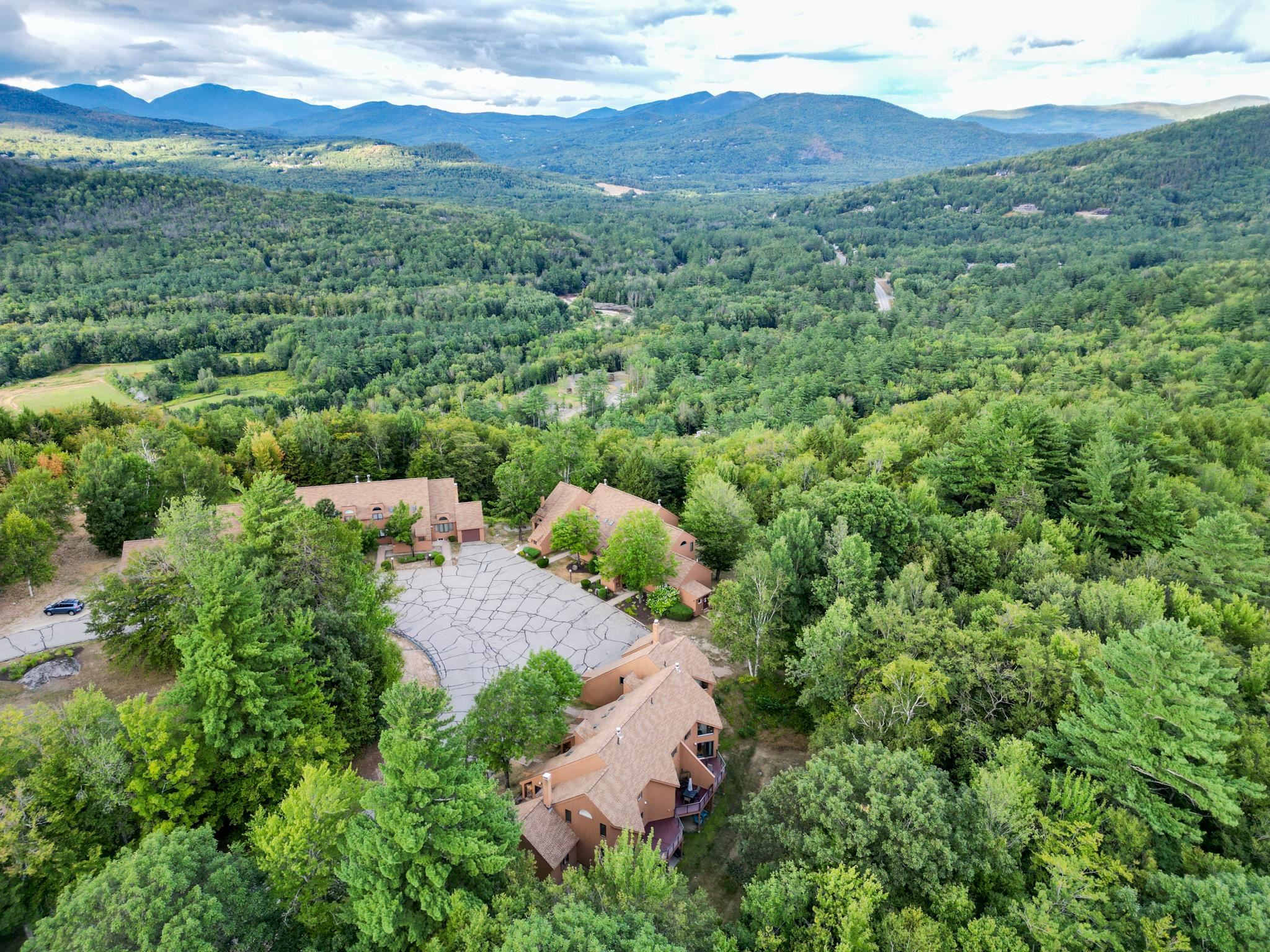 Aerial view of forest-surrounded condominiums with distant mountain ridges.