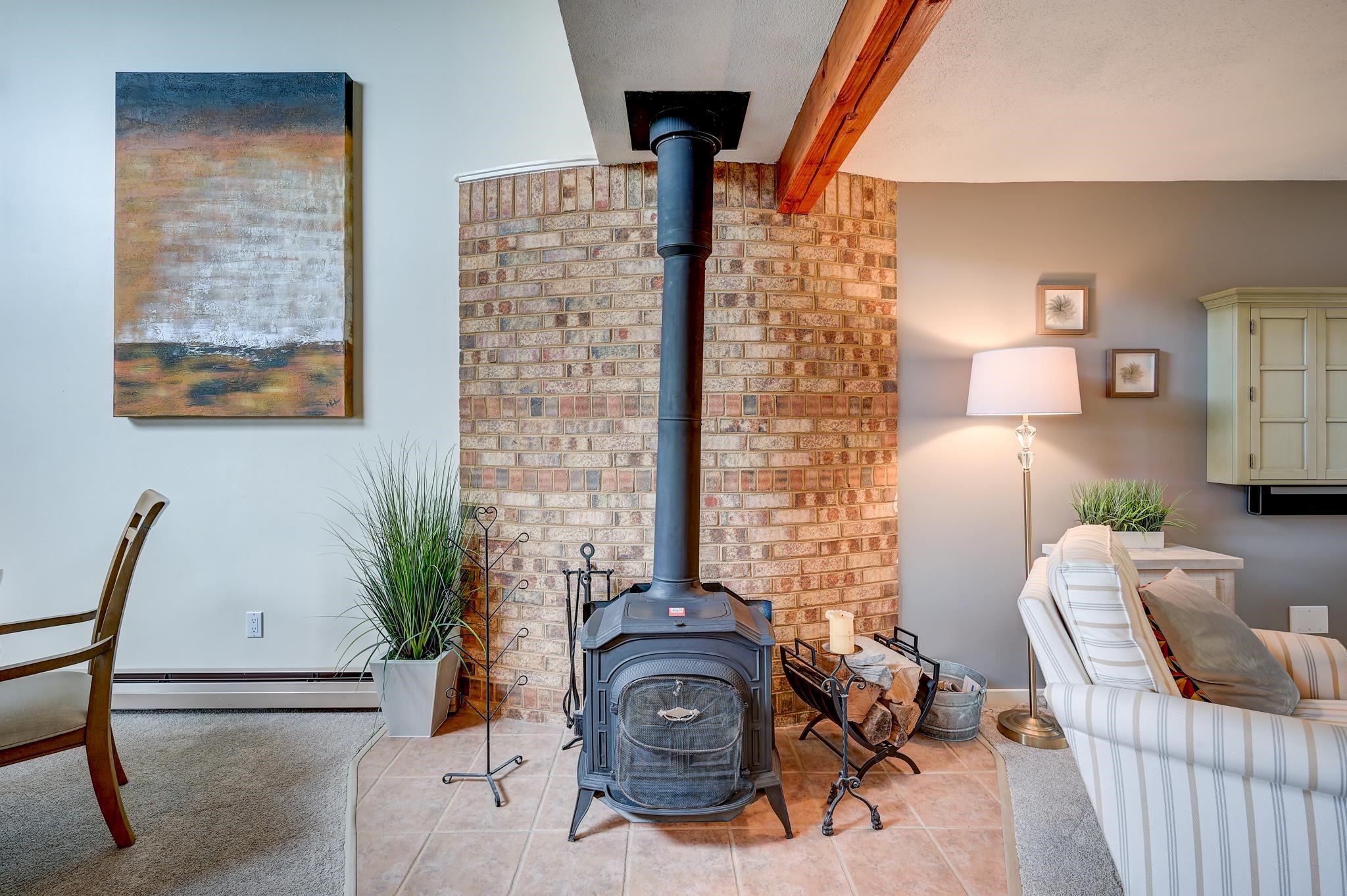 Furnished living room with a freestanding wood stove, brick surround, and tiled hearth.