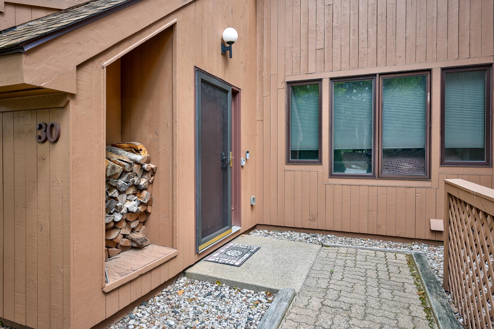 Unit 30 entrance with stacked firewood in a recessed alcove beside the front door.