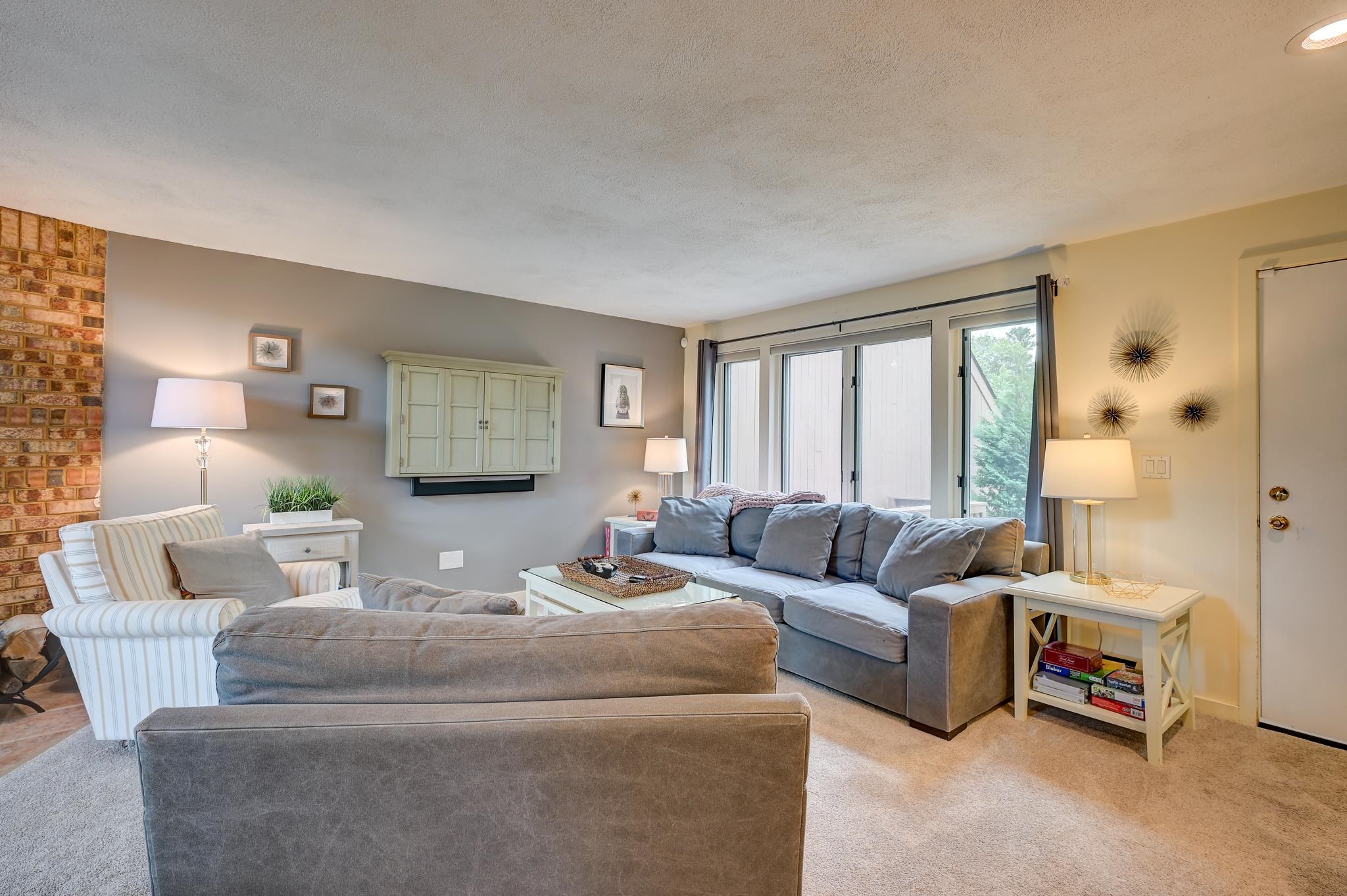 Living room with gray sofas, a striped armchair, and sliding glass doors.