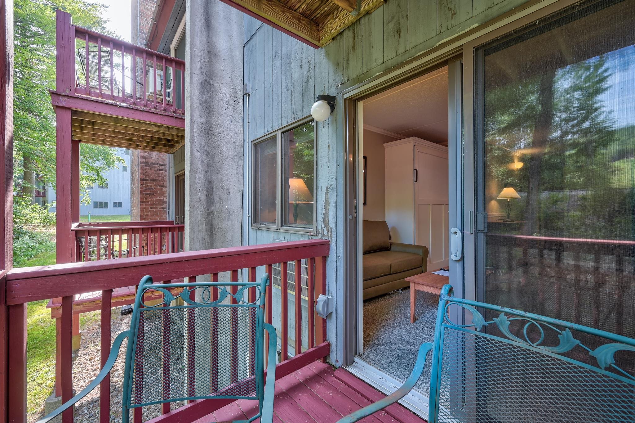 Condo balcony with turquoise chairs and an open sliding door to the living area.