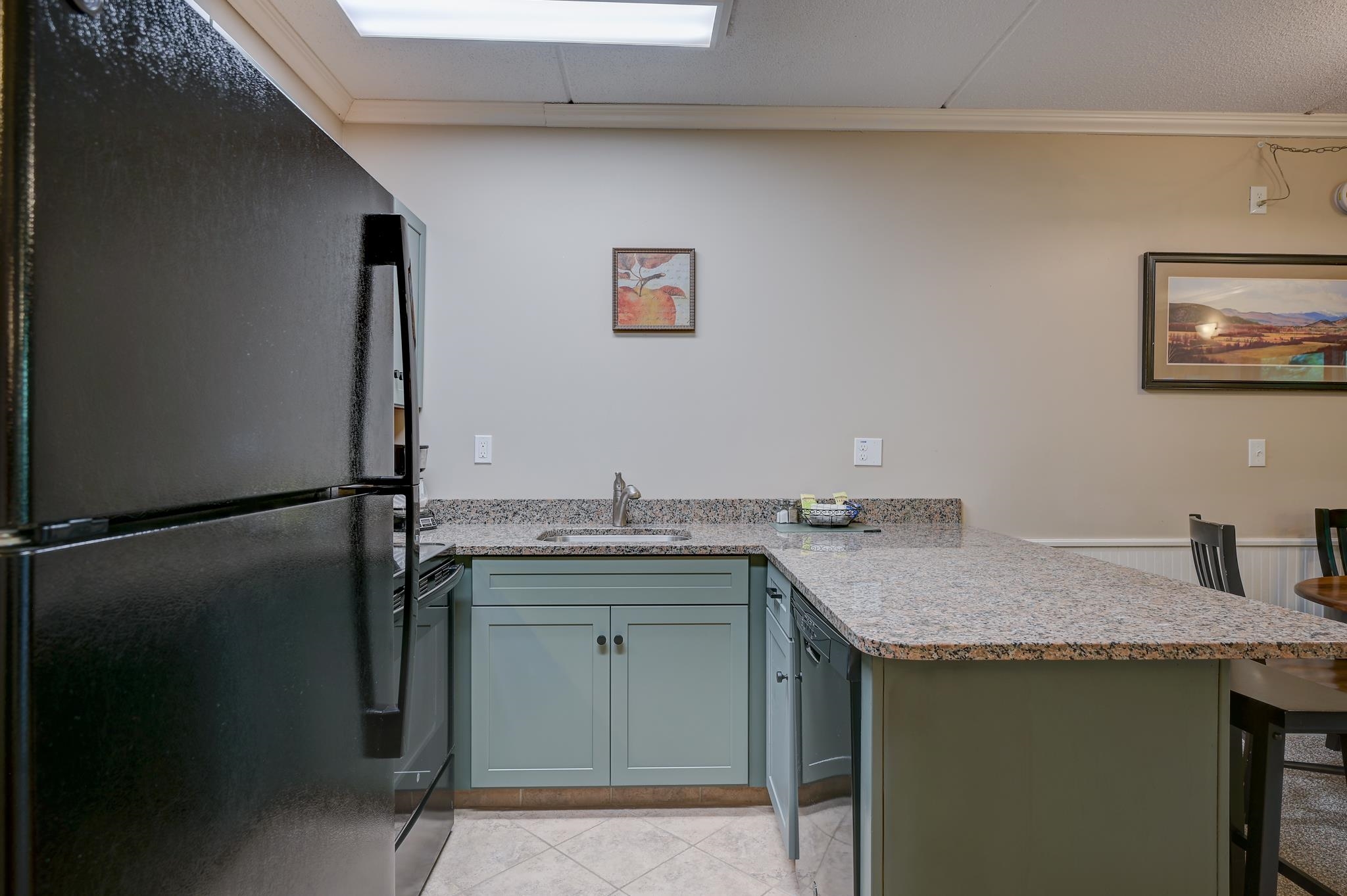 Kitchen with blue-gray cabinets, granite counters, a breakfast bar, and black refrigerator.