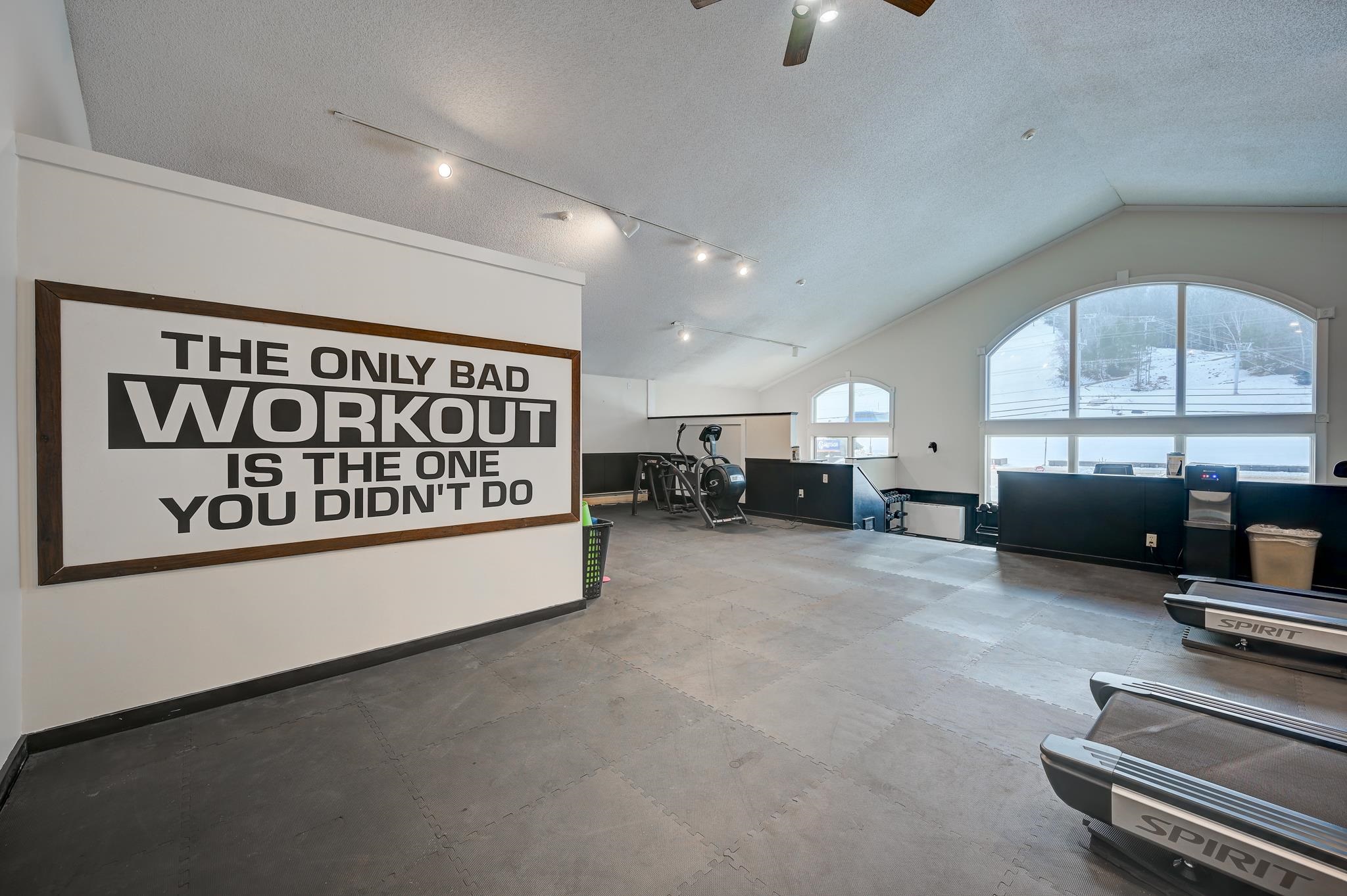 Condominium fitness room with treadmills, exercise equipment, and a large motivational wall sign.