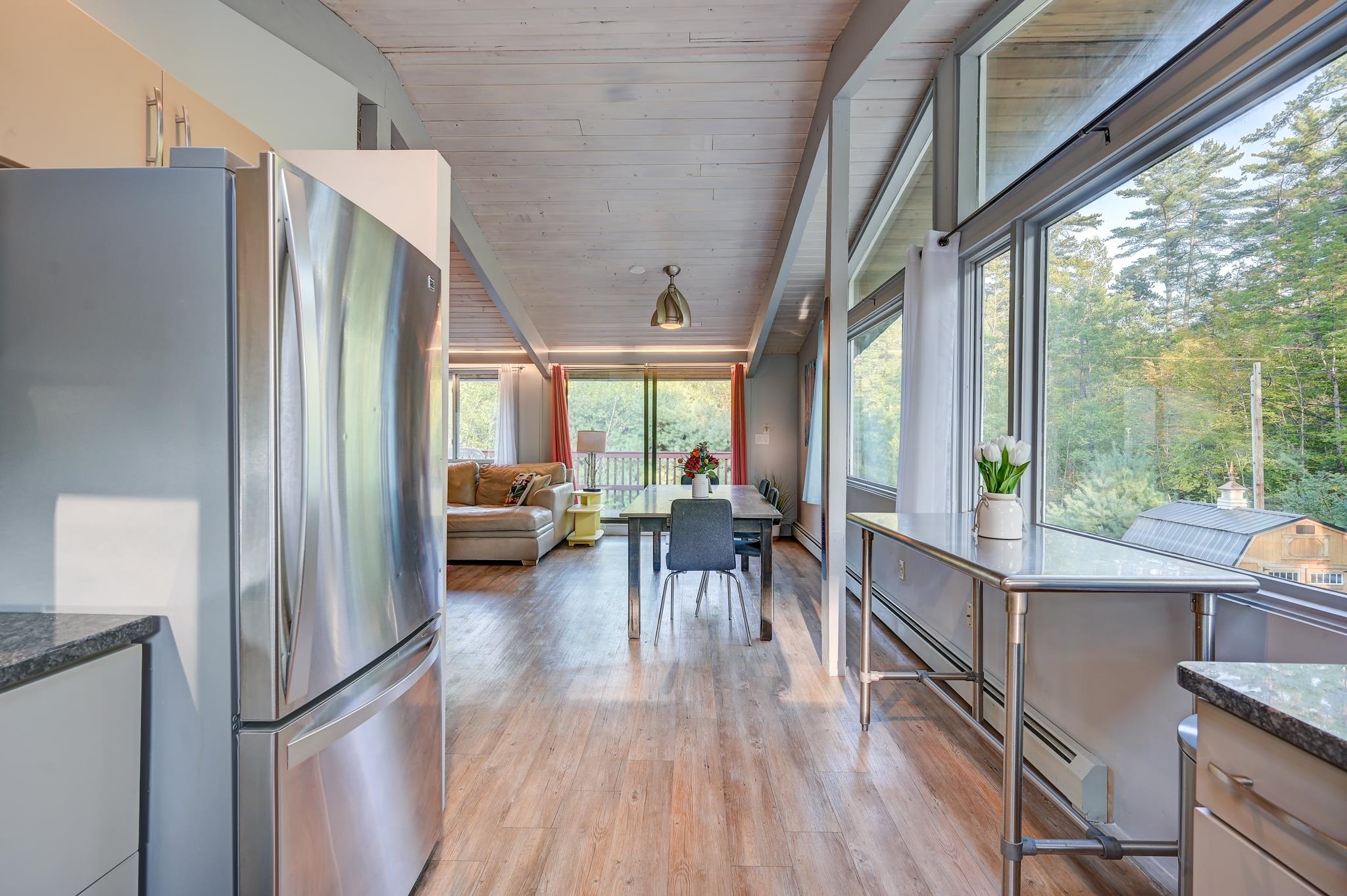 Open-plan kitchen and dining area with floor-to-ceiling windows overlooking trees.