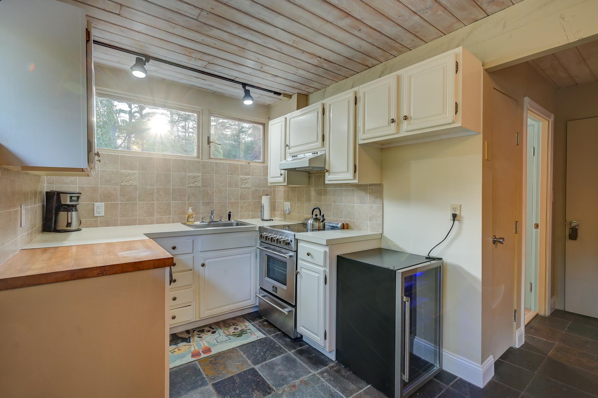 Kitchen with white cabinets, a wood-plank ceiling, and a glass-front beverage refrigerator.