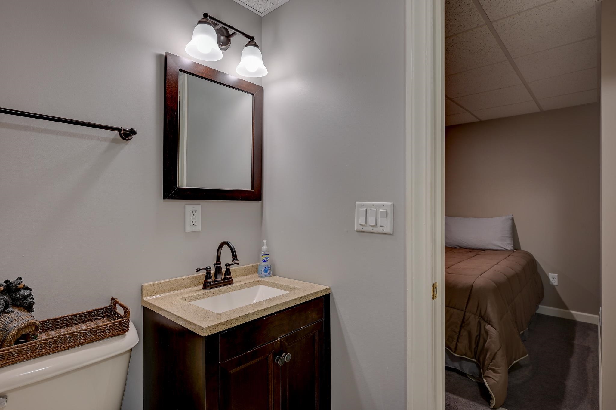 Bathroom vanity with a framed mirror and open doorway to a bedroom.