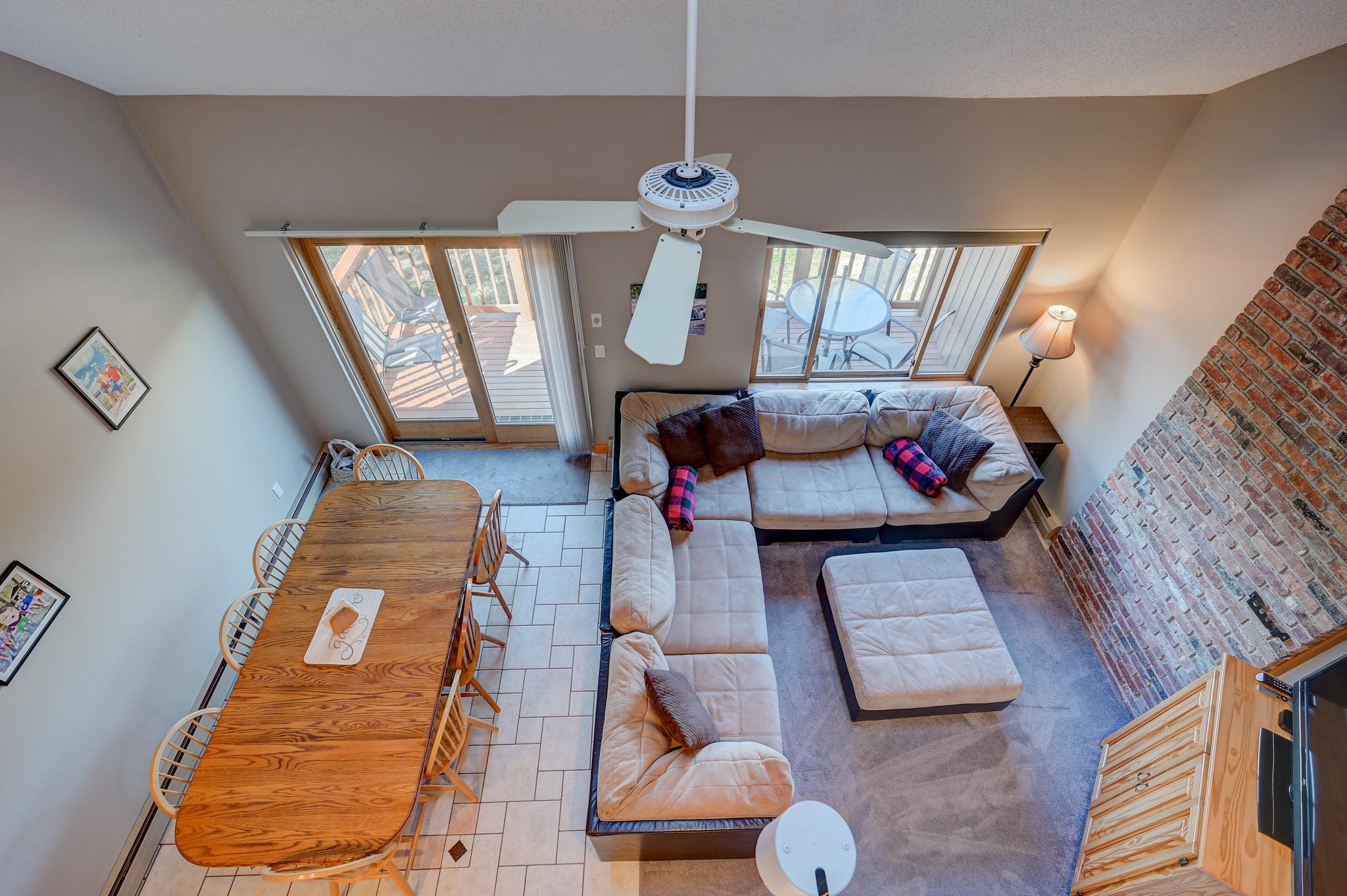 Living room and dining area with a sectional sofa, brick fireplace, and sliding doors to a deck.