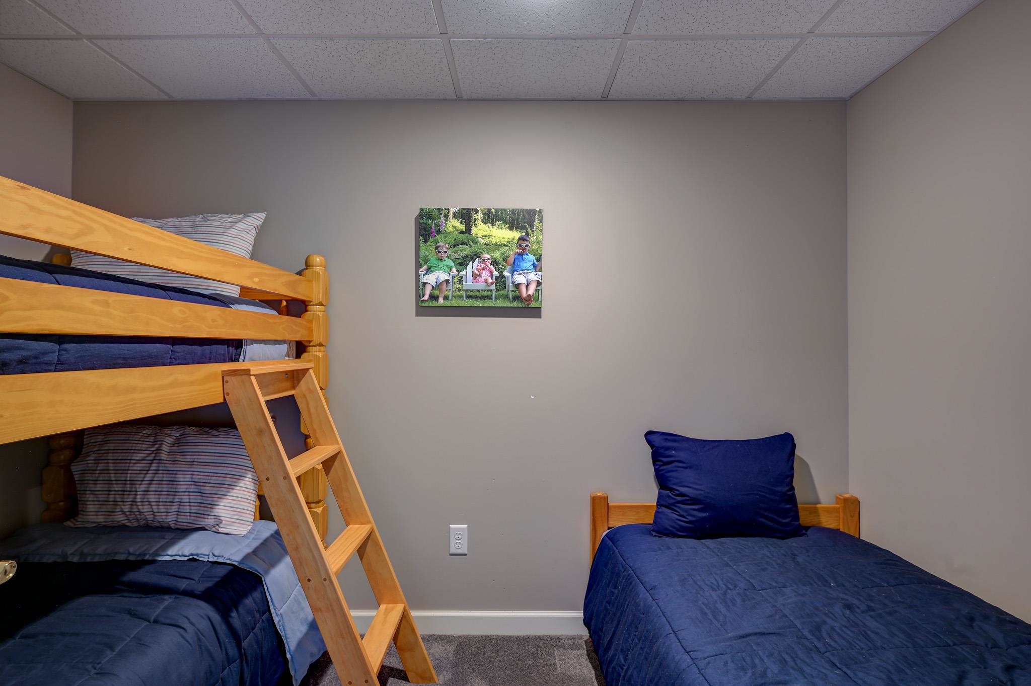 Bedroom with a wooden bunk bed and a separate single bed dressed in navy bedding.
