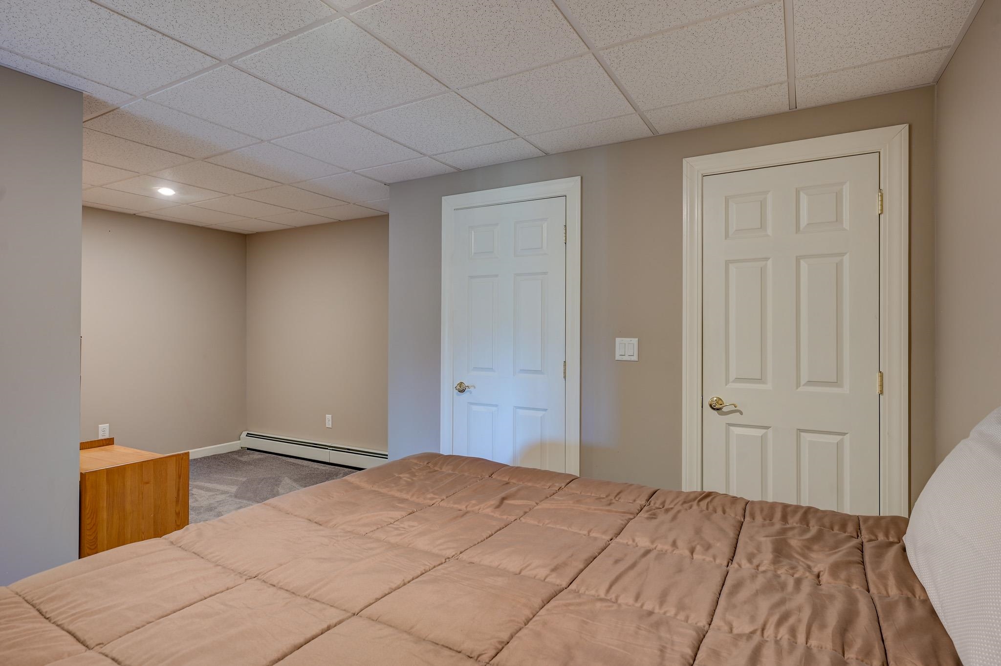 Bedroom with a tan quilted bed, gray carpet, and two white paneled doors.