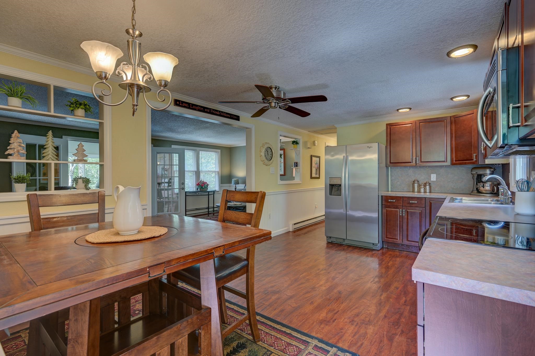 Kitchen and dining area with dark wood cabinets, stainless steel appliances, and a wooden table.