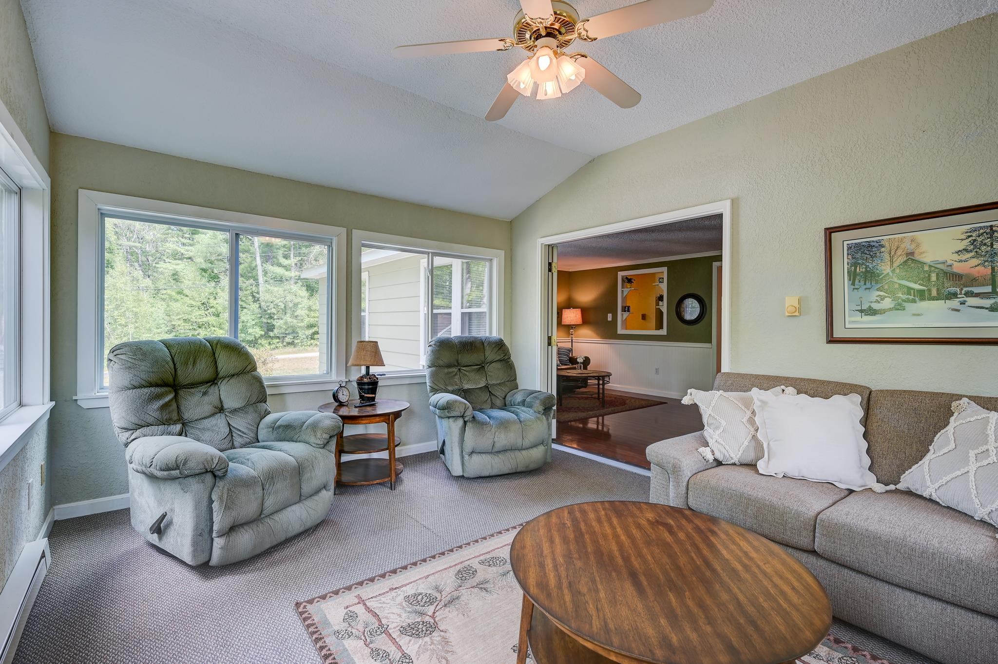 Living room with large tree-facing windows, two recliners, and a gray sofa.