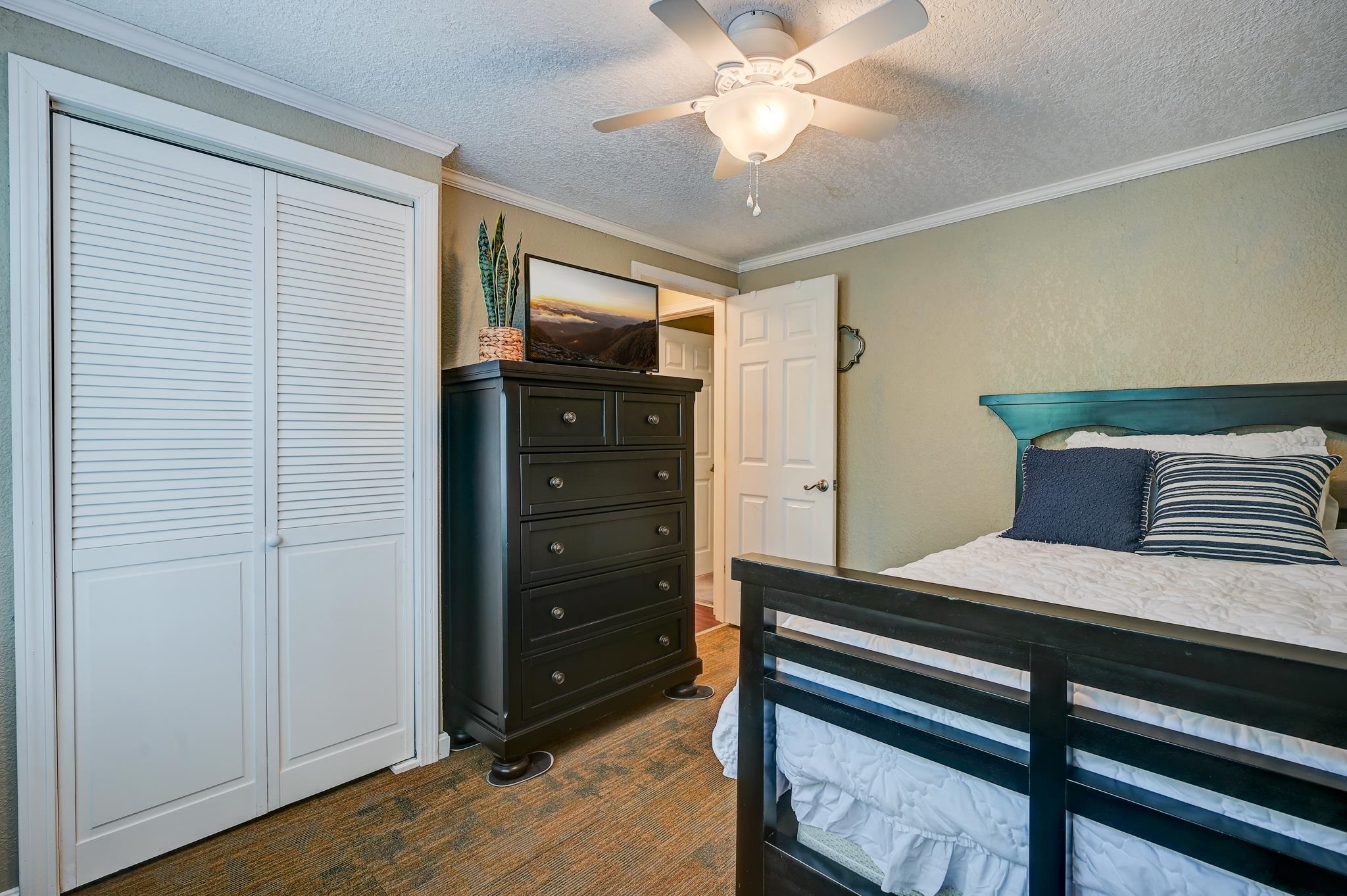 Bedroom with a black slatted bed, dark dresser, and white louvered closet doors.
