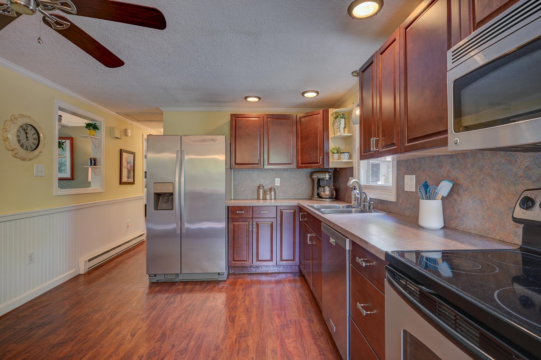Kitchen with reddish-brown cabinets, stainless steel appliances, and a sink beneath a window.