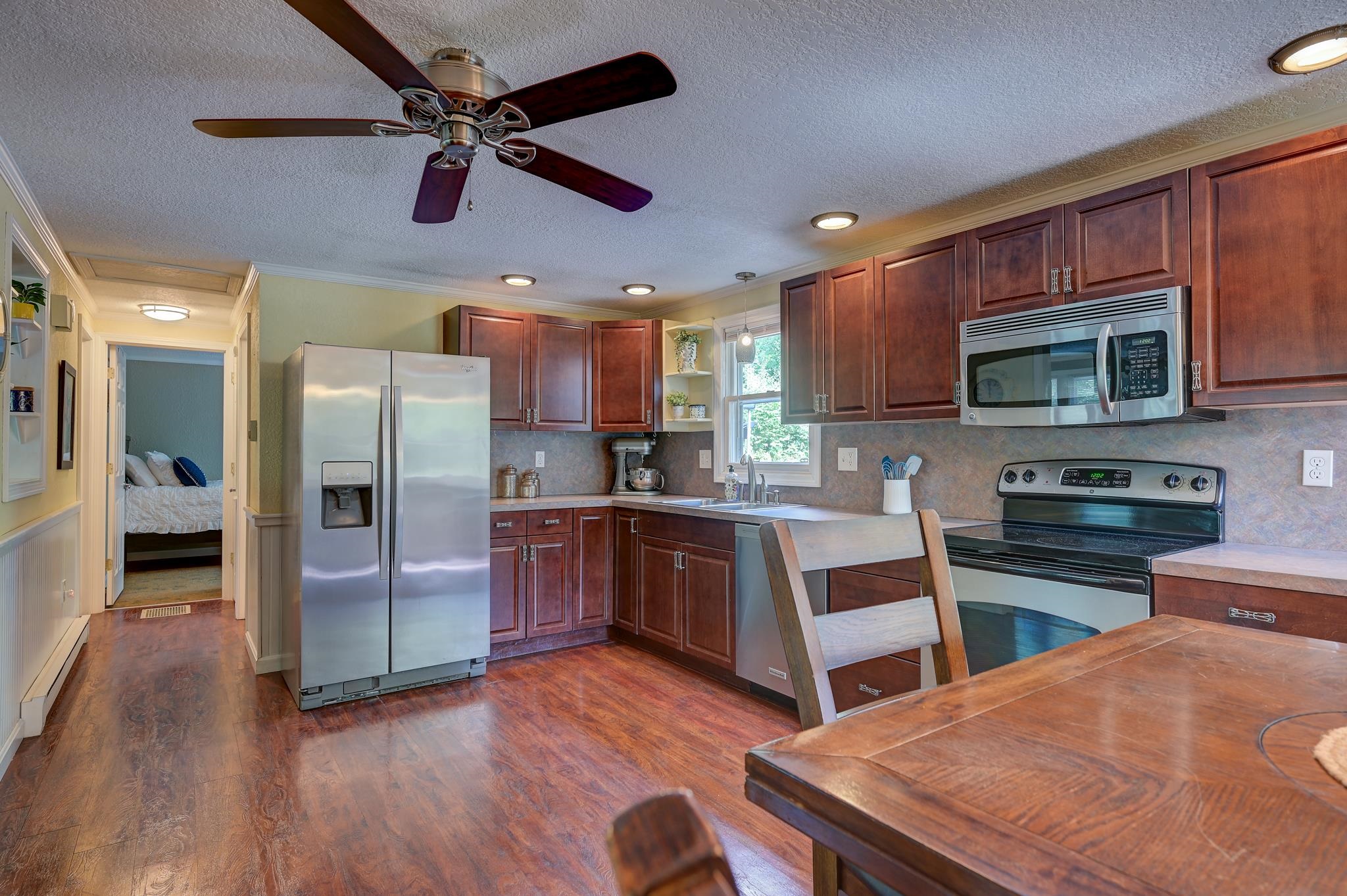 Kitchen with cherry cabinets, stainless steel appliances, and a doorway opening to a bedroom.