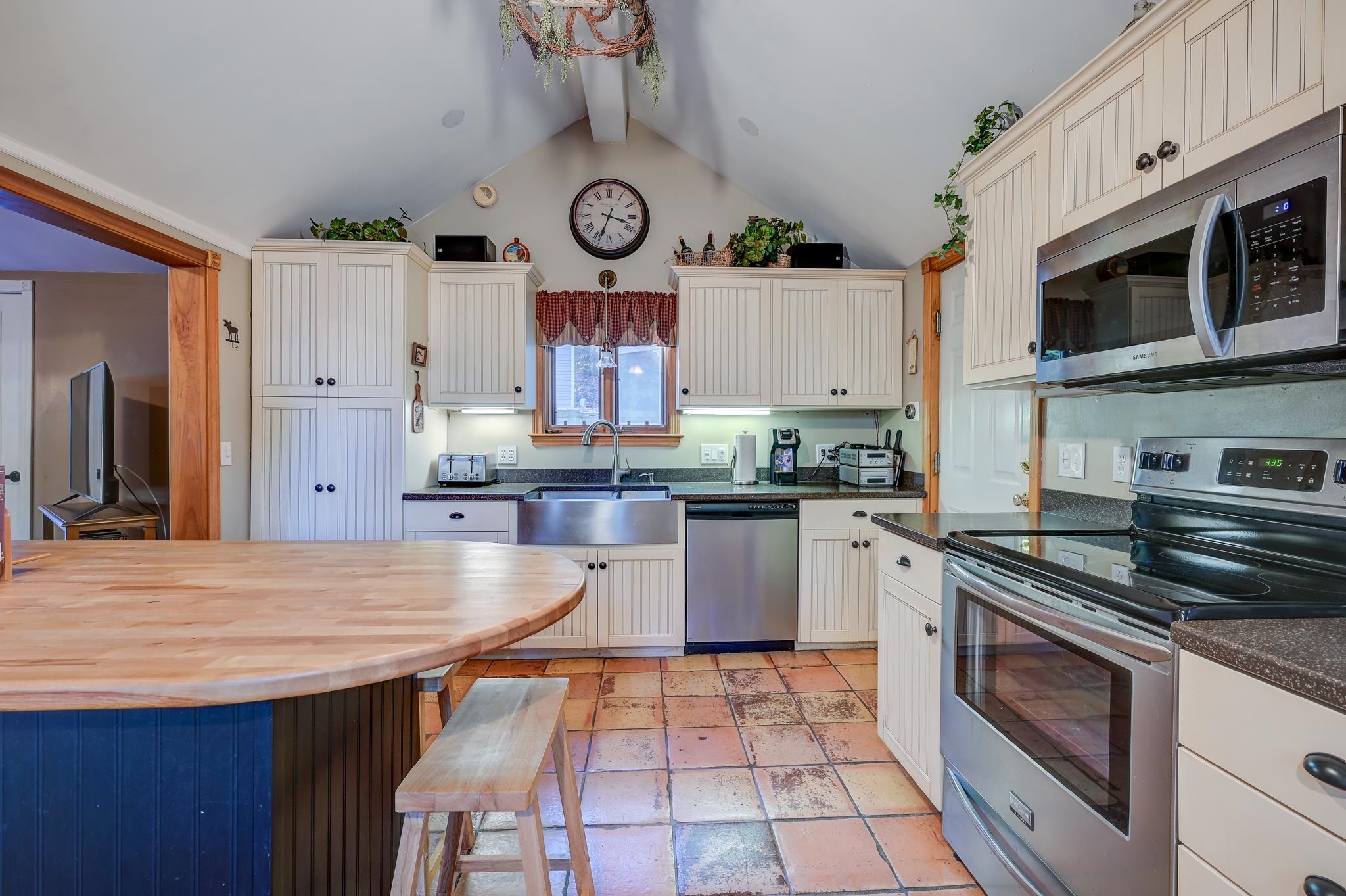 Kitchen with white paneled cabinets, stainless steel appliances, and a round butcher-block island.