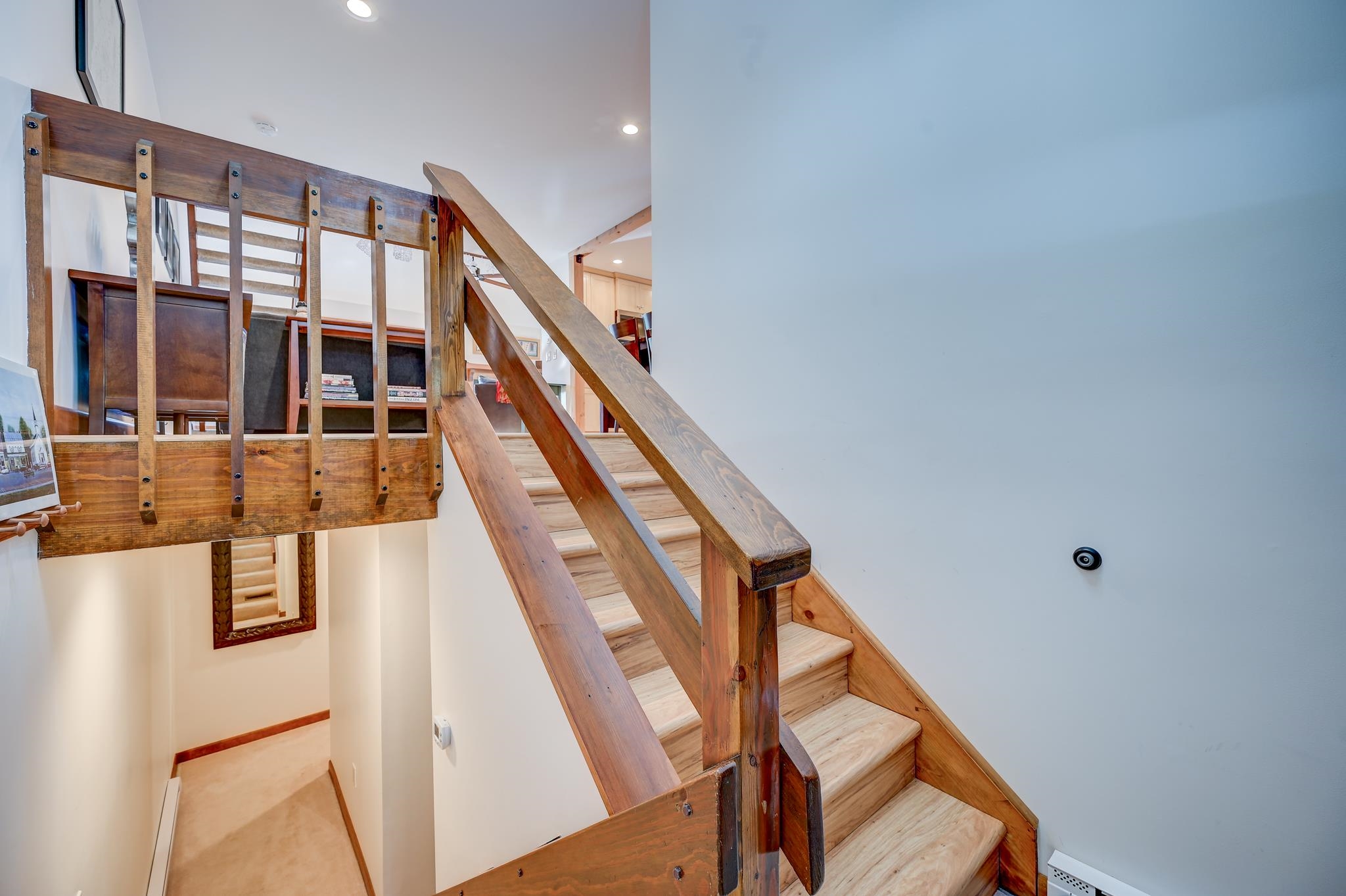 Wooden staircase with pale treads and heavy timber railings leading to an open loft landing.