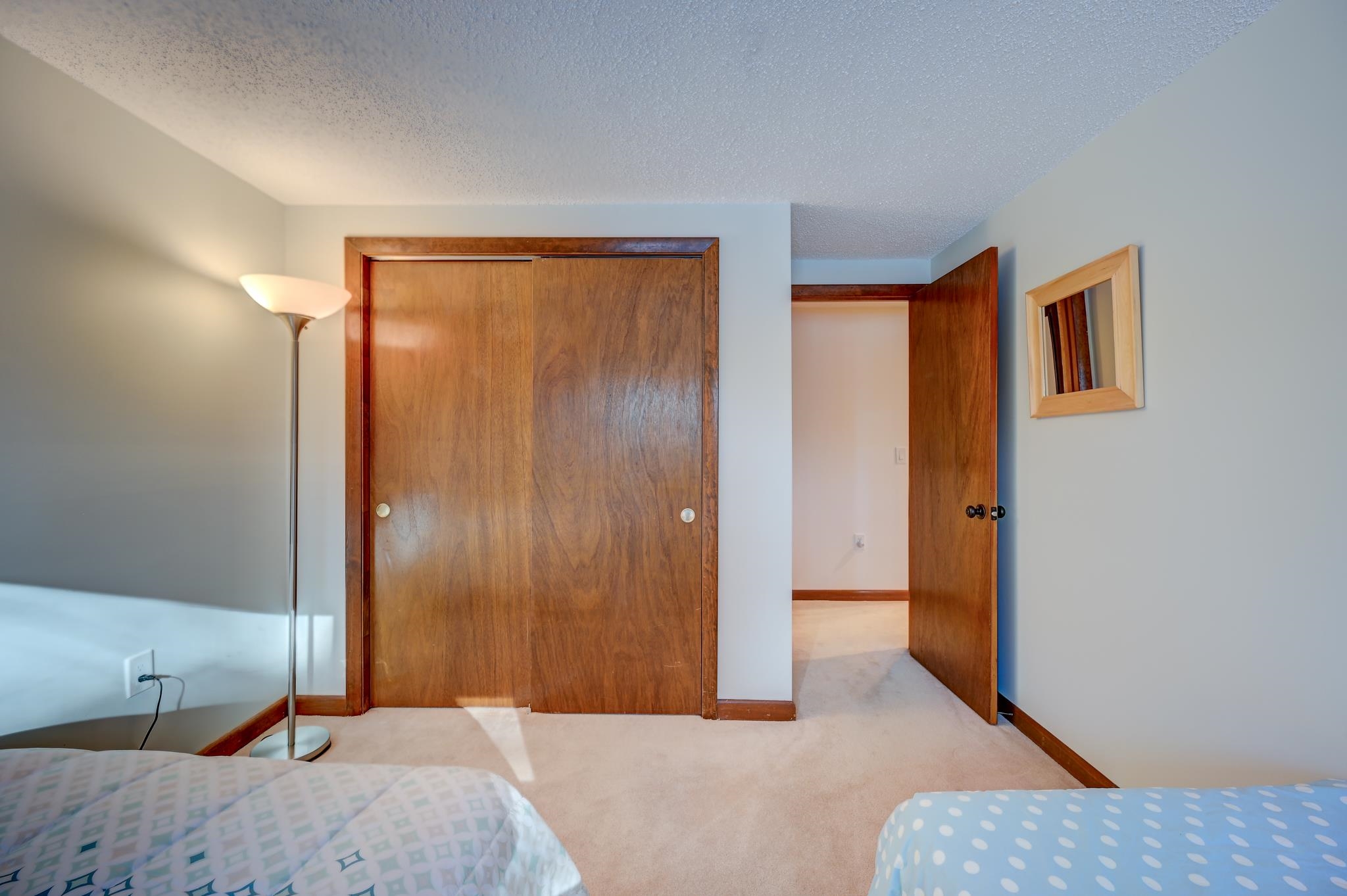 Bedroom with two beds, a large wooden closet, and an open door to the hallway.