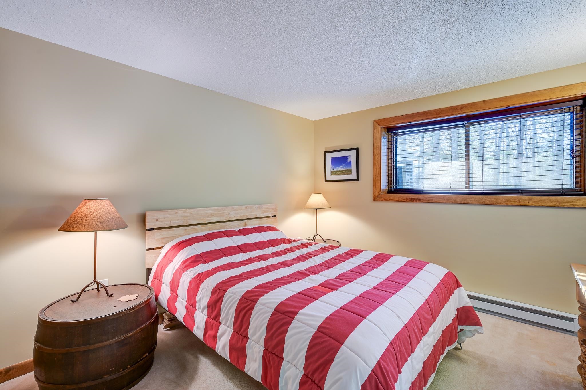 Bedroom with a red-and-white striped quilt and a wide wood-trimmed window.