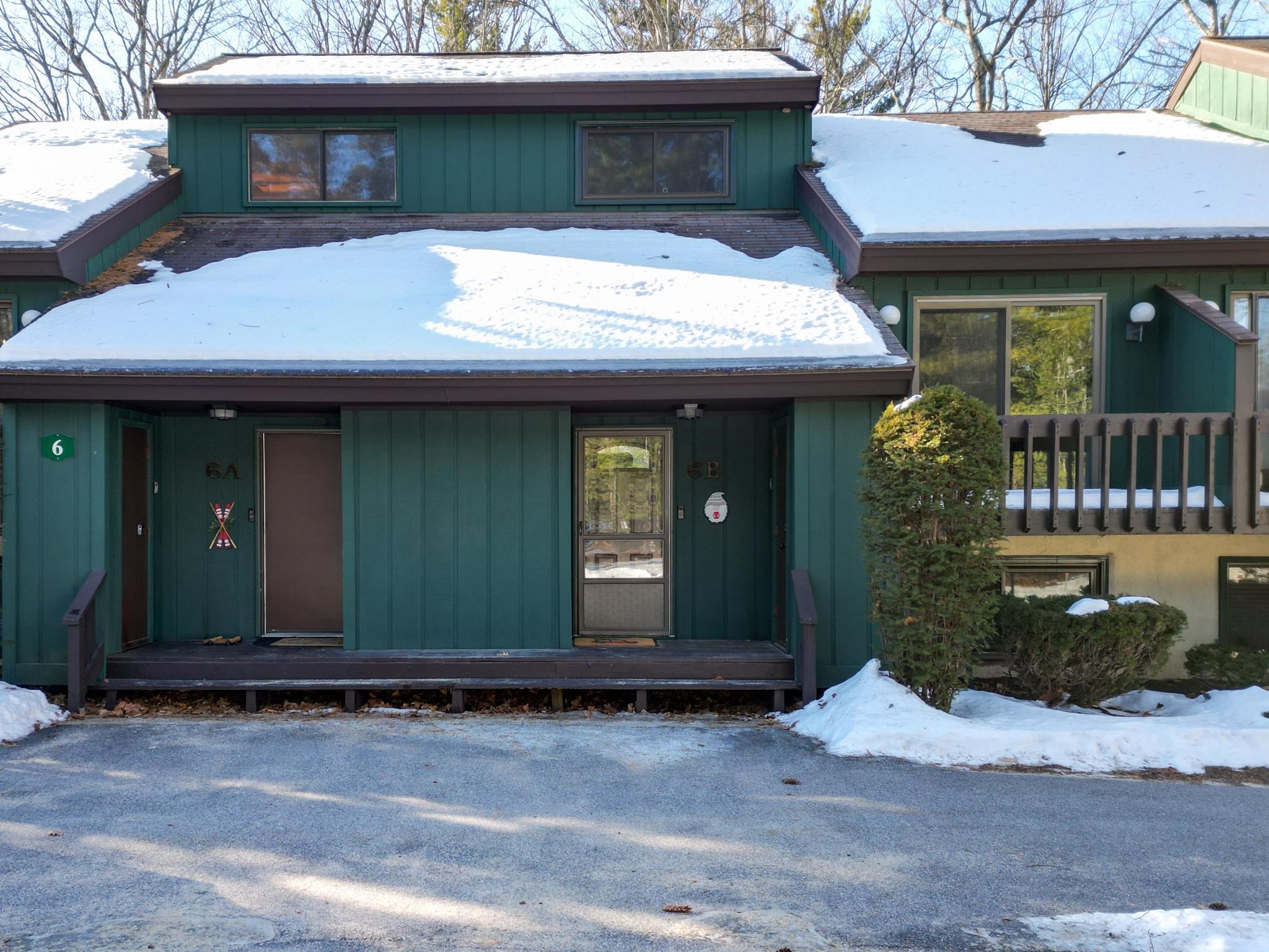 Green condominium exterior with snow-covered roofs and the Unit 6B entrance beside Unit 5A.