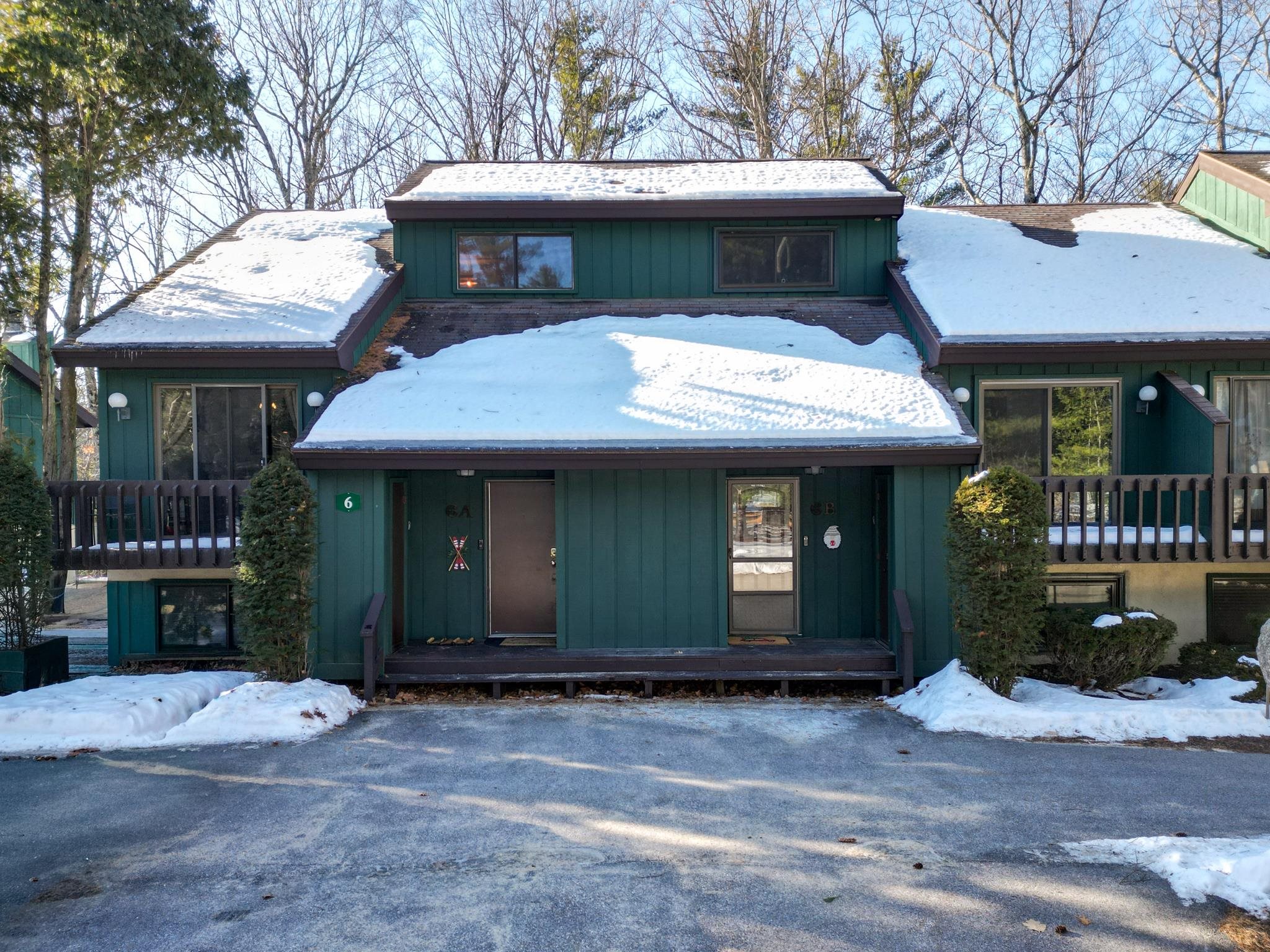 Green condominium exterior with snow-covered roofs and a covered entrance.