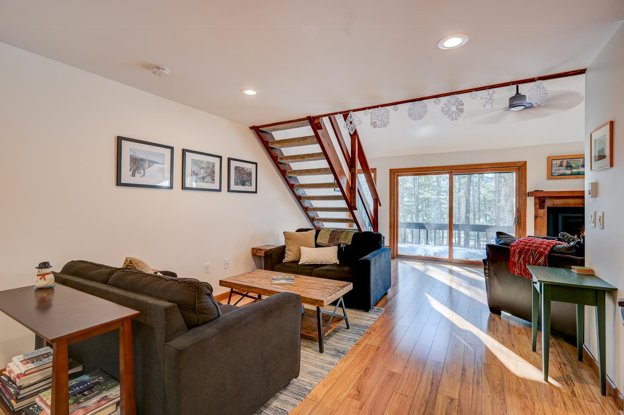 Living room with an open staircase, hardwood floors, sliding glass doors, and a fireplace.
