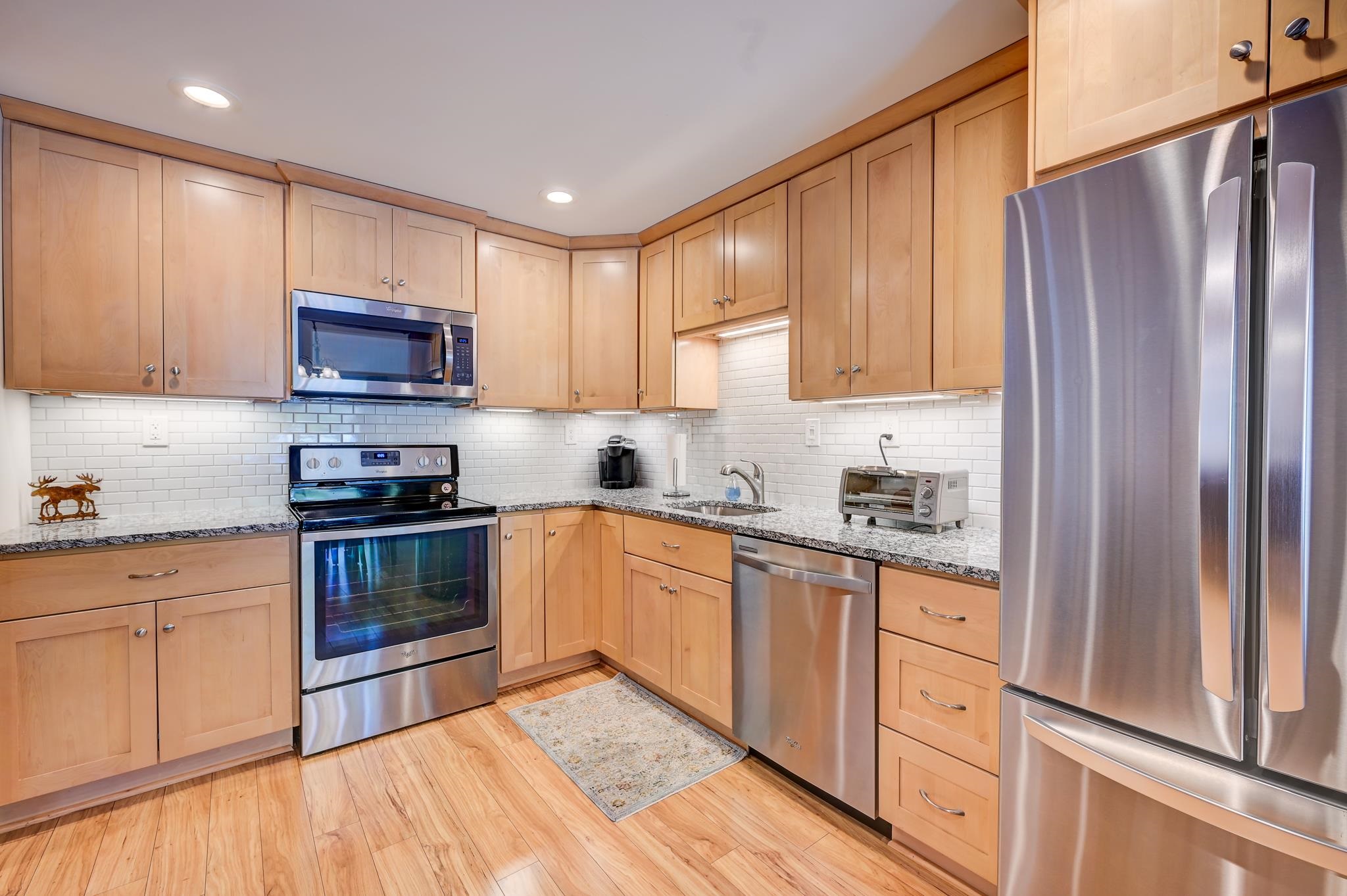Kitchen with light wood cabinets, granite counters, and stainless steel appliances.