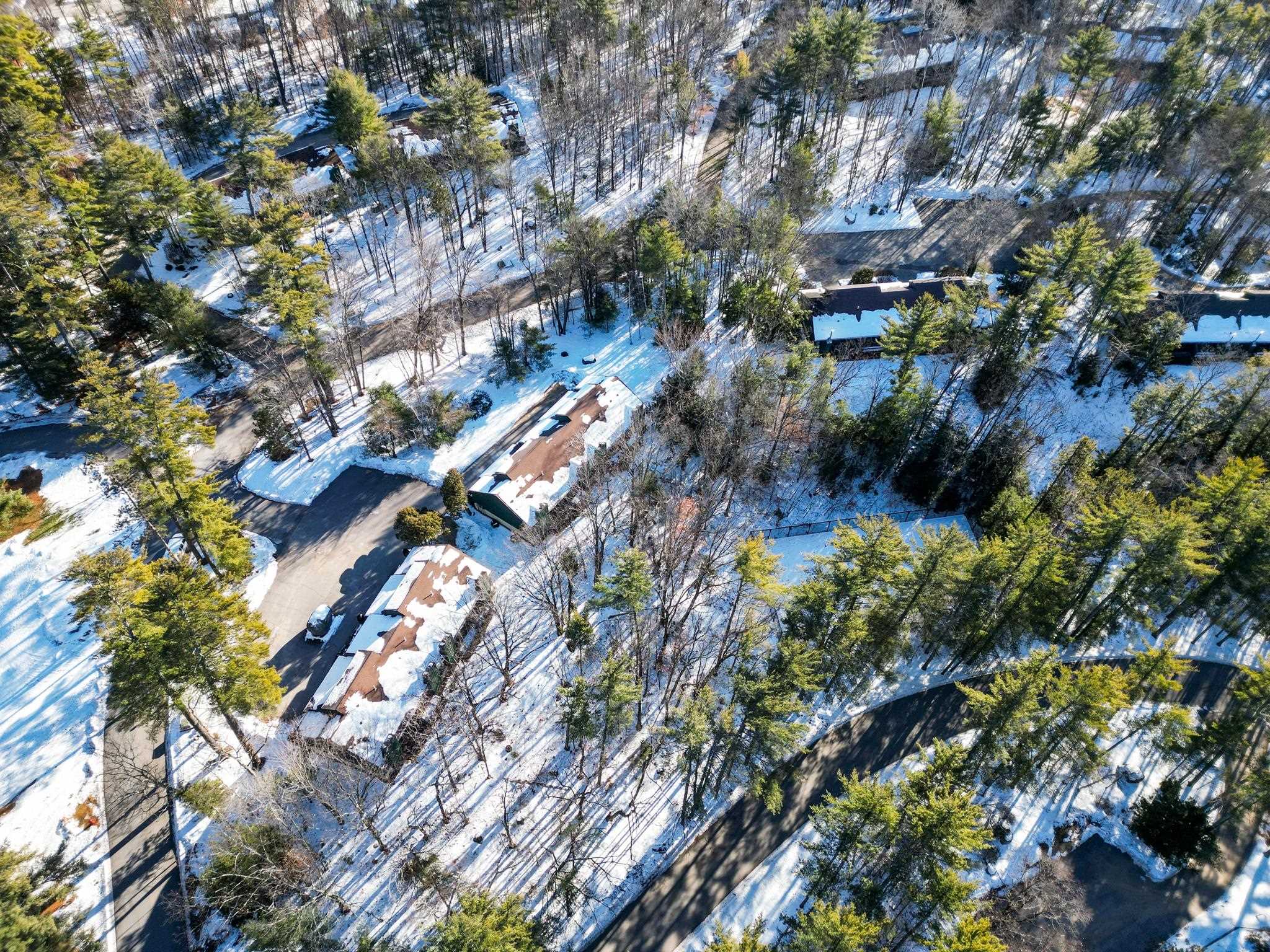 Aerial view of snow-covered condominium buildings and winding roads among trees.